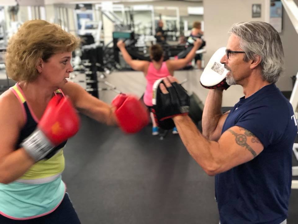 Vern Gauthier assists a client in boxing exercises at Fit For You Health Club.