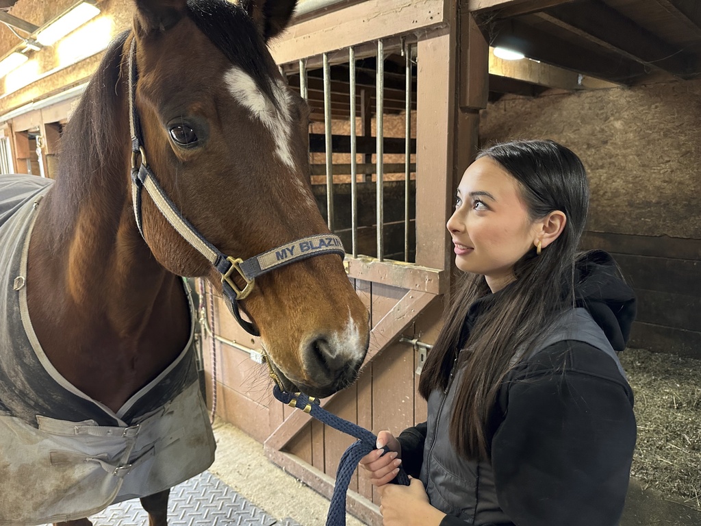 Kylie Ossege looks at her horse, Blaze, at a boarding facility Saturday, Nov. 11, 2023, in Mayfield Township, Mich. Ossege was severely injured in a 2021 mass shooting at Oxford High School and says spending time with Blaze provides her with a measure of comfort. (AP Photo/Mike Householder)