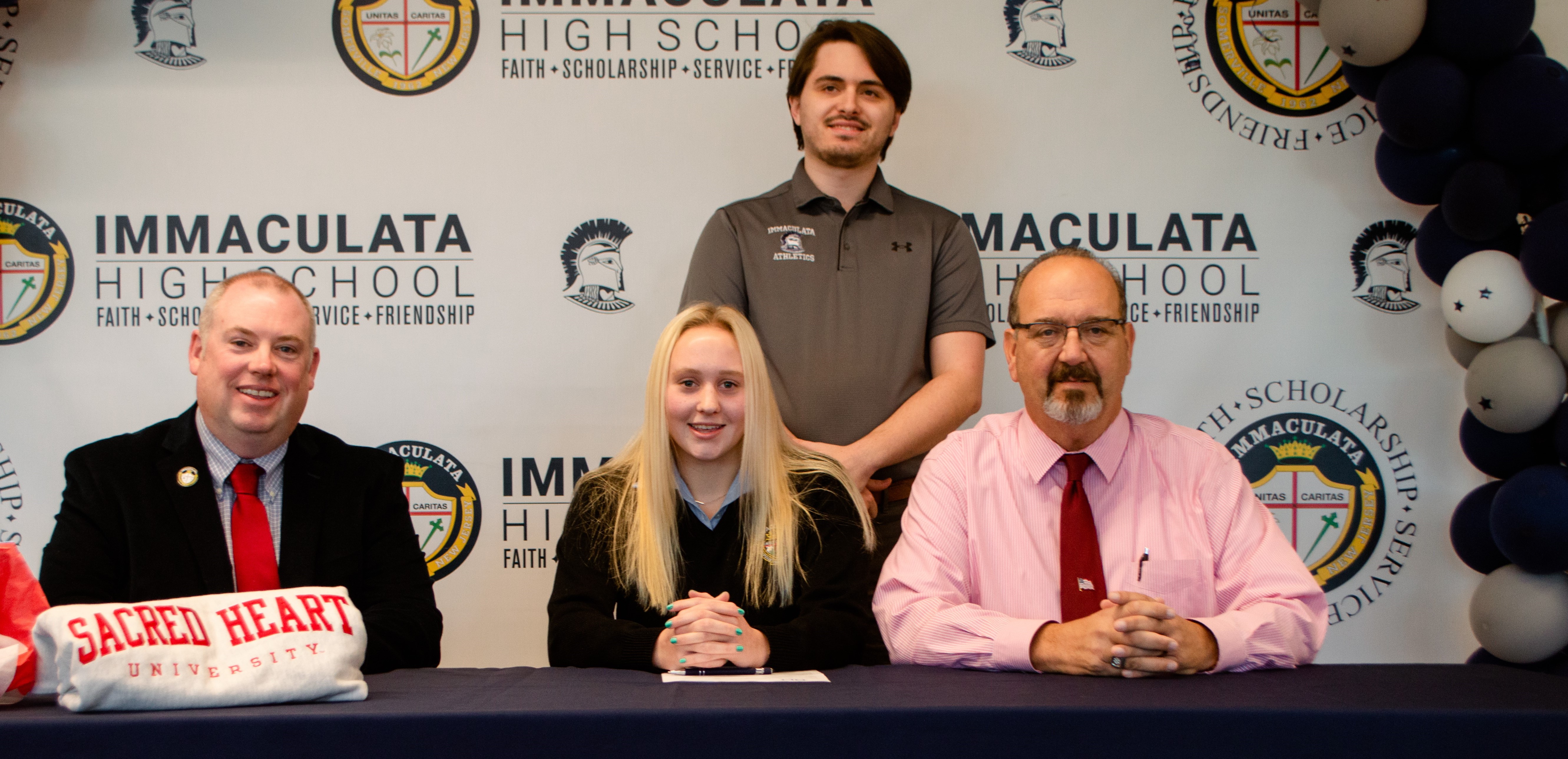 Immaculata's Maeve English signs her NLI to Sacred Heart for swimming with Principal Ed Webber, AD Tom Gambino, and swim coach William Corman