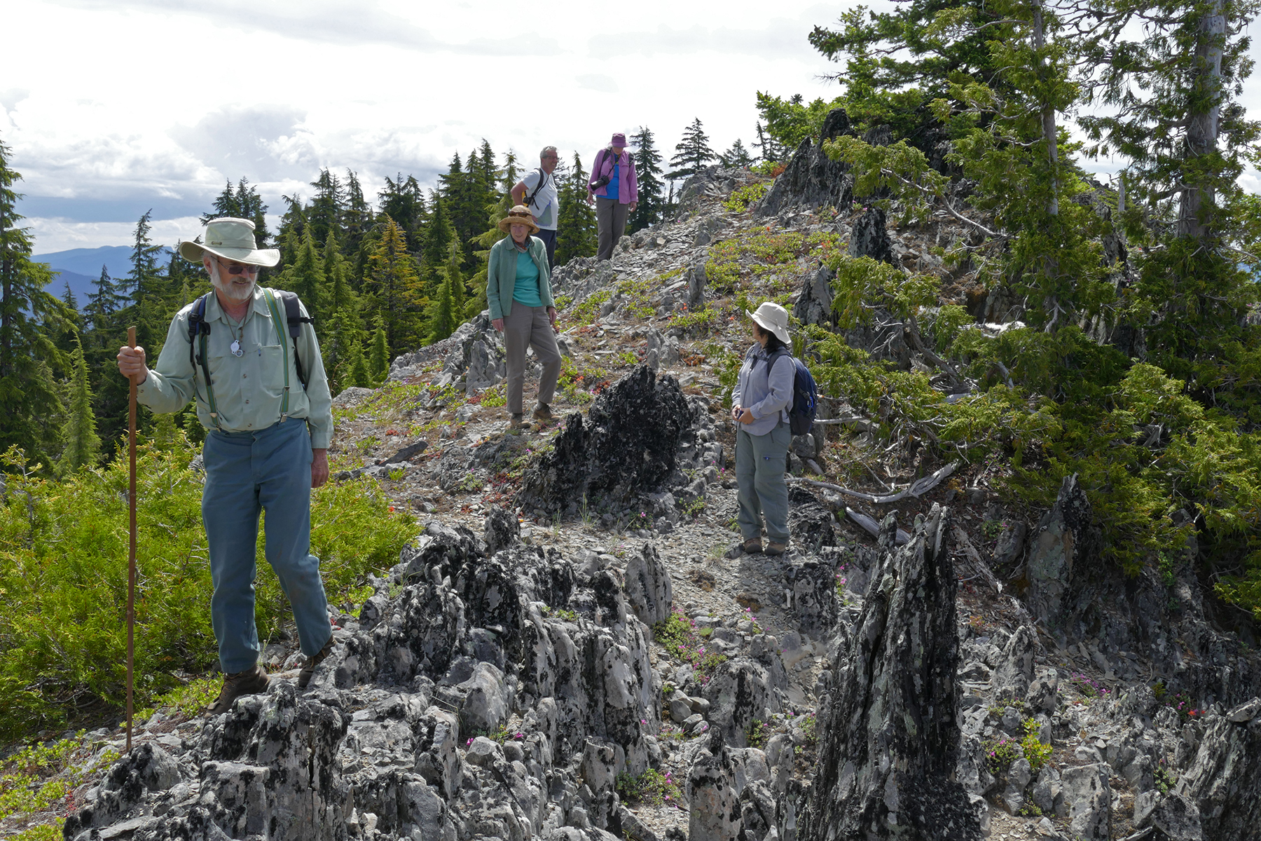 A group of people is shown walking over a rock terrain on a mountaintop