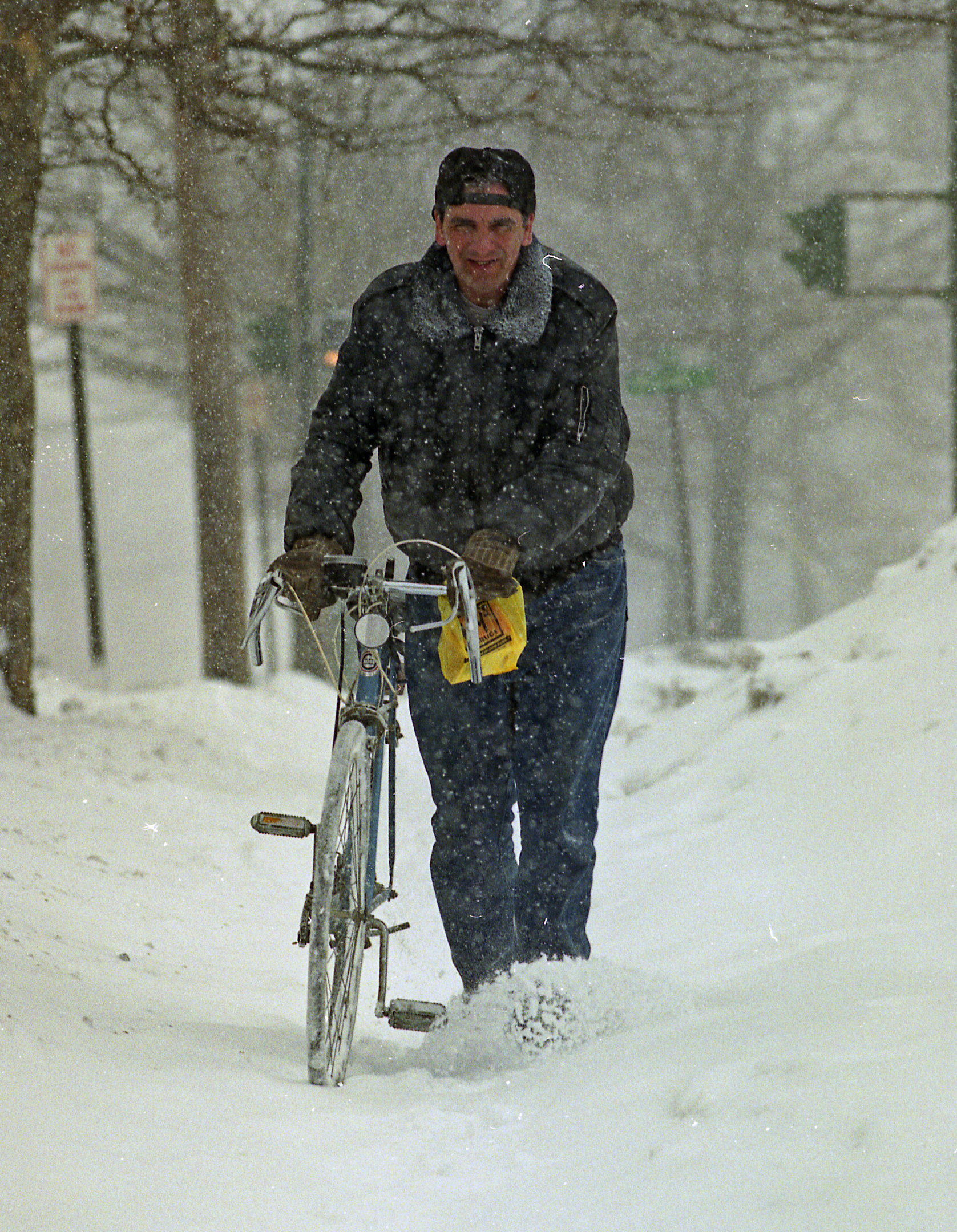 John Managan, who works at the Public Safety Building, walks his bike through the snow after work on James Street, Syracuse.  He was able to ride it to work earlier in the day. During the Blizzard of 1993.