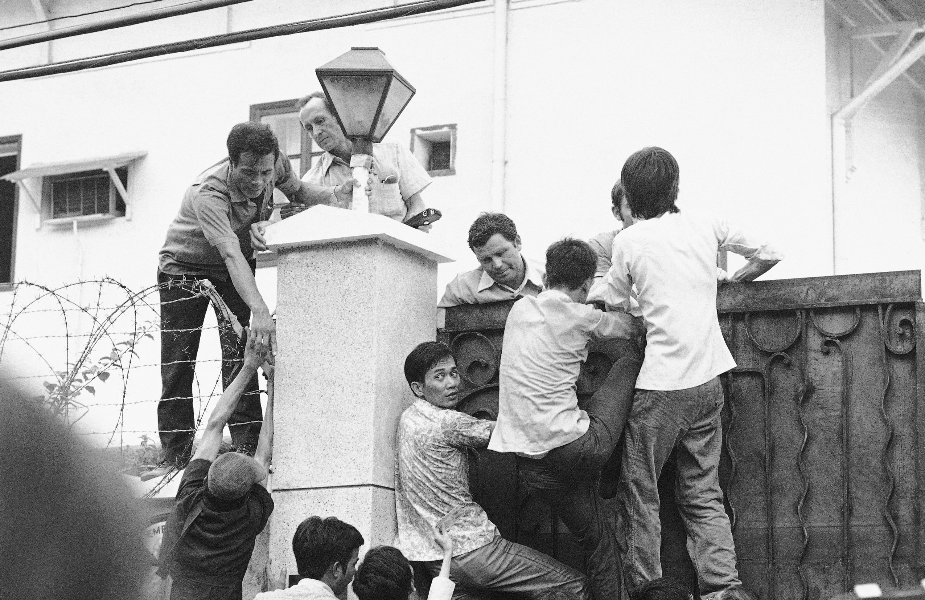 Vietnamese try to scale the high U.S. Embassy wall in desperate attempts to get aboard the evacuation flights in Saigon, May 1, 1975. (AP Photo)