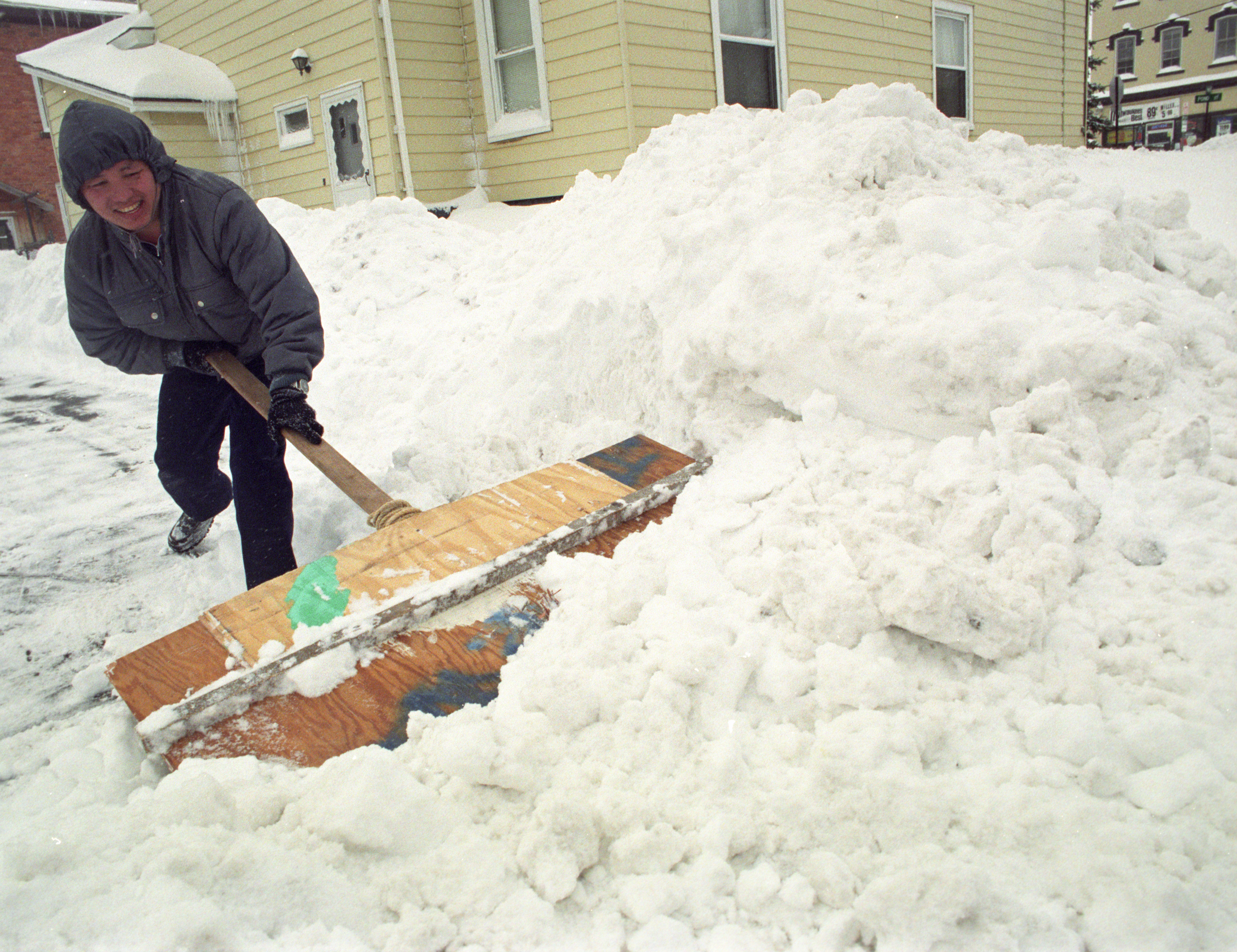 Cher Pao Vang of Syracuse uses a home made shovel to clear snow from his driveway from a storm that dumped some 40 inches of snow on the area. Nicholas Lisi / The Post-Standard