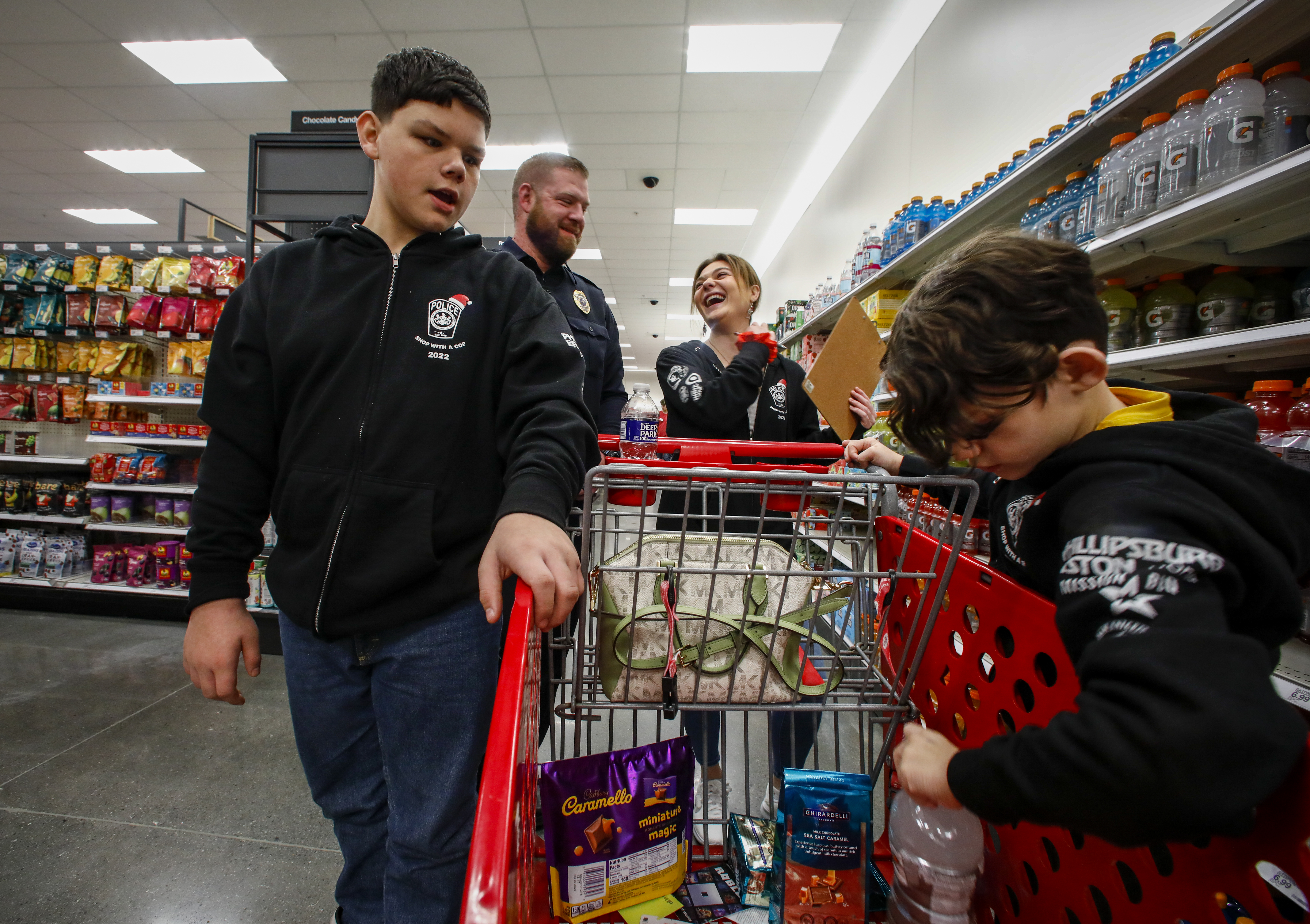 Officer Ian Macleod and Catasauqua Teacher Marlaina Riegel, share a laugh as they escort Dylan Gaguski, 13, left, and his brother Jacob Thompson, 10, right, around Target in Hanover Township on Saturday, Dec. 3, 2022, as they select items to buy during a holiday shopping spree. 