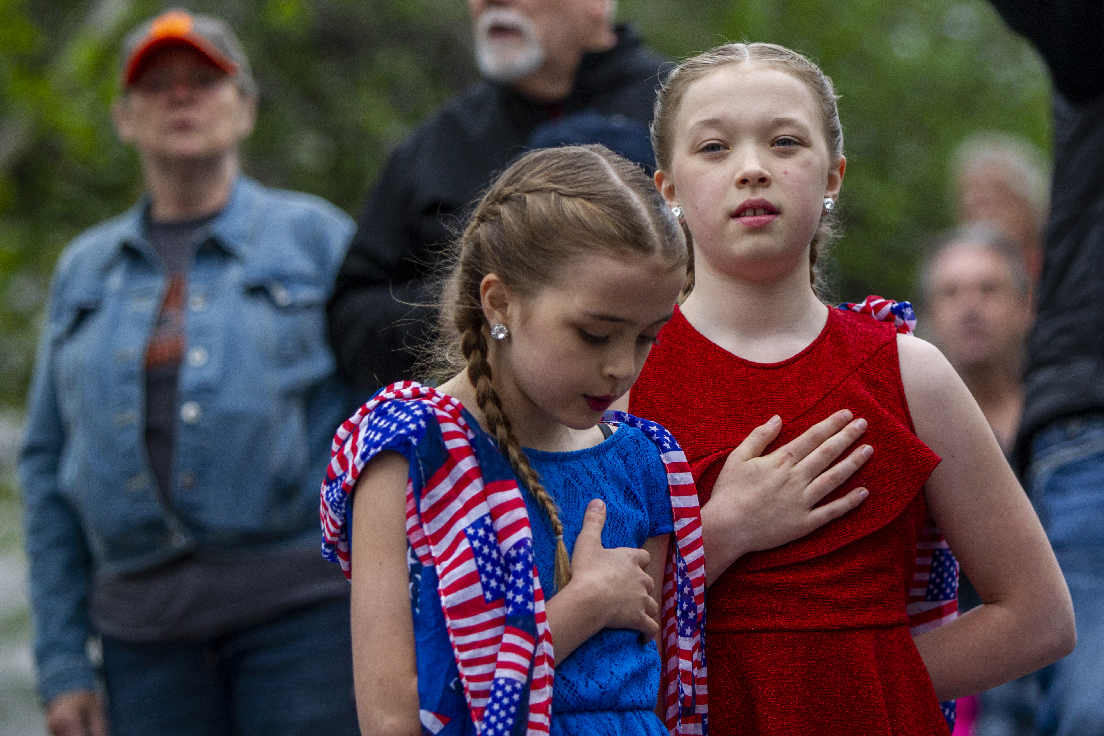 Gracee, 10, left, and Hayden Heikkila, 13, stand for "The Star-Spangled Banner" during the "American Patriot Rally-Sheriffs speak out" event at Rosa Parks Circle in downtown Grand Rapids on Monday, May 18, 2020. The crowd is protesting against Gov. Gretchen Whitmer's stay-at-home order. The sisters are from Battle Creek. (Cory Morse | MLive.com)