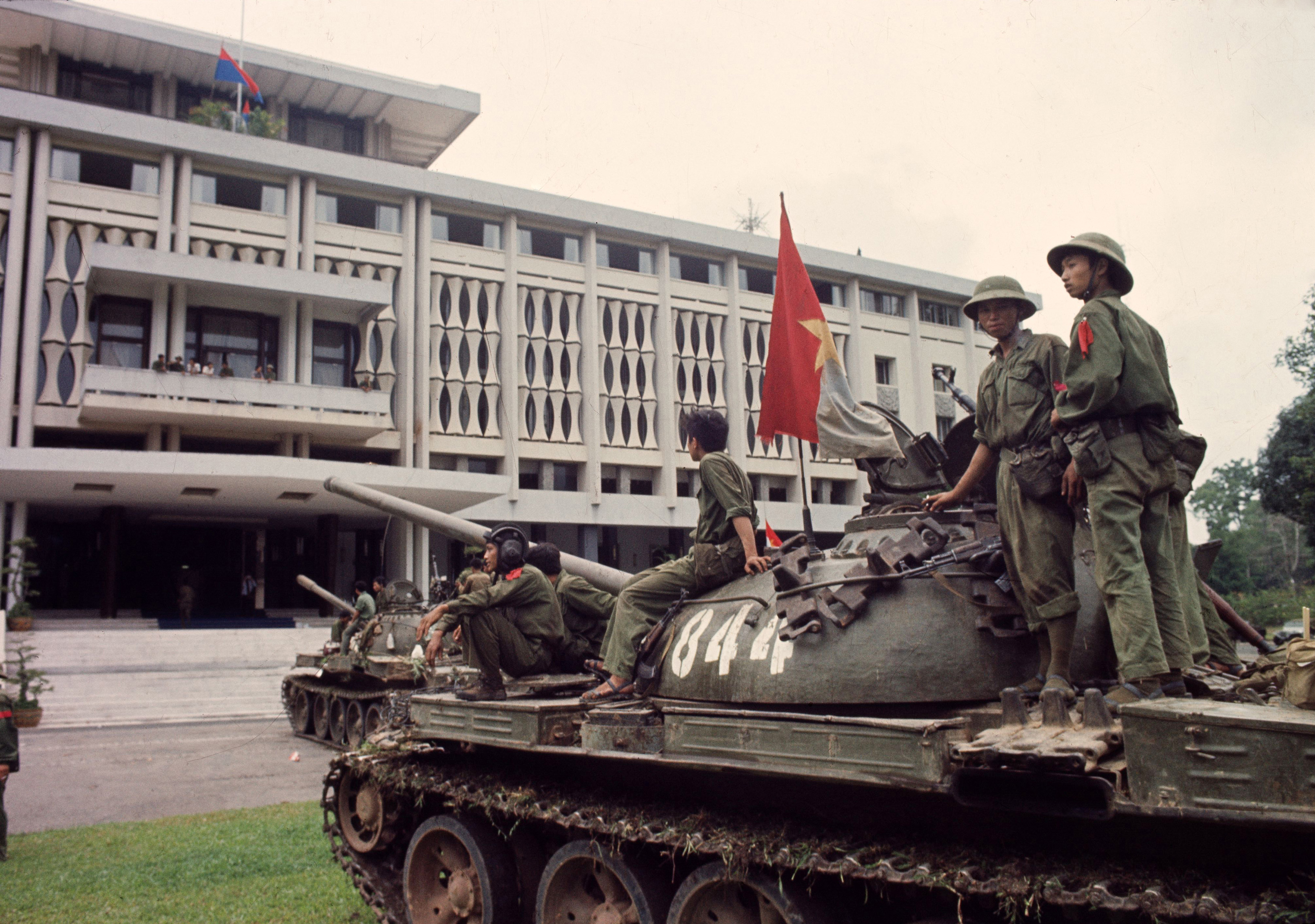 Victorious North Vietnamese troops on tanks take up positions outside Independence Palace in Saigon, April 30, 1975, the day the South Vietnamese government surrendered, ending the Vietnam War. Communist flags fly from the palace and the tank. (AP Photo/Yves Billy)