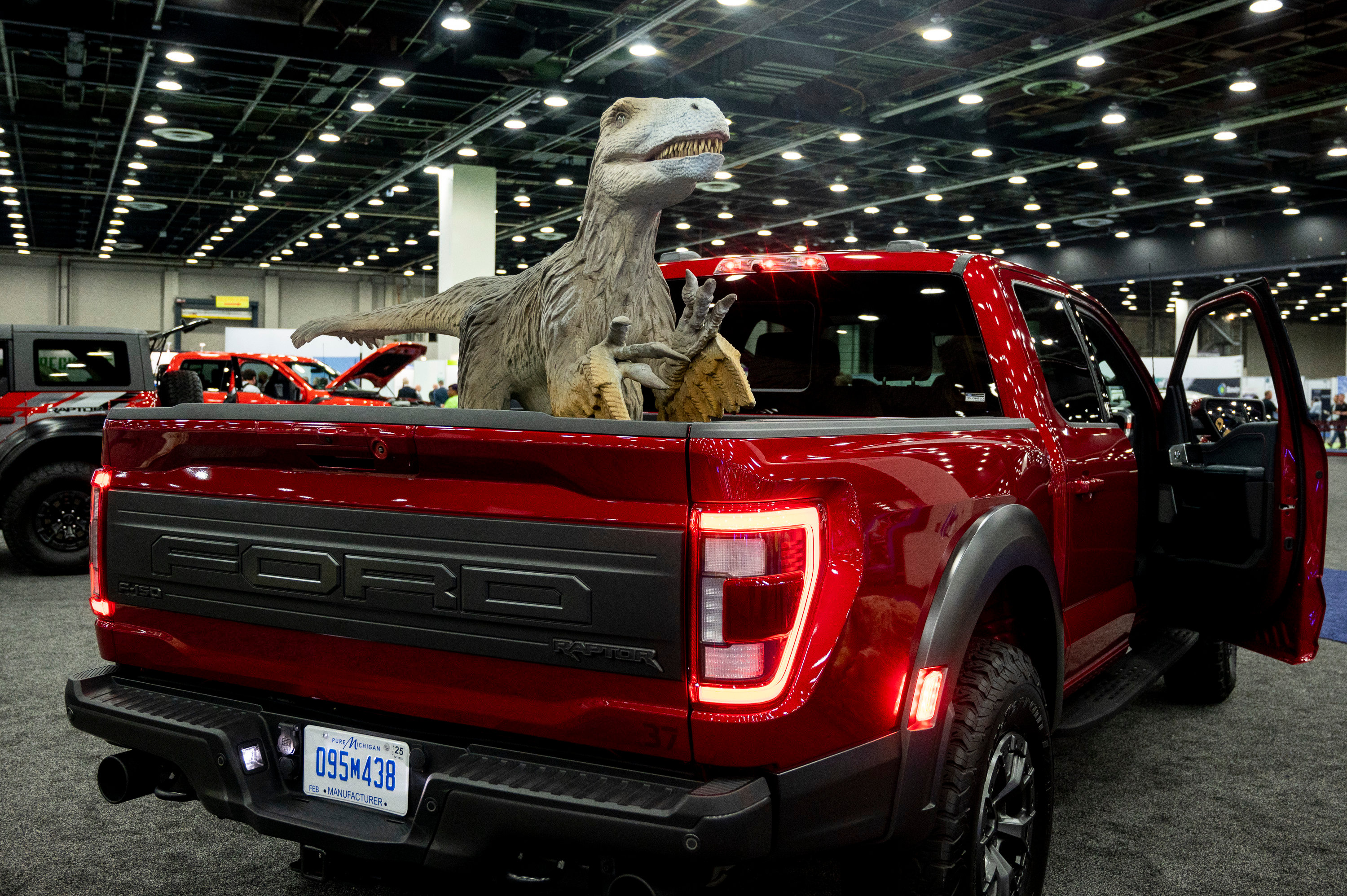 A dinosaur statue sits in the bed of a Ford F-150 Raptor on display during the 2022 North American International Auto Show at Huntington Place in Detroit on Wednesday, Sept. 14 2022.