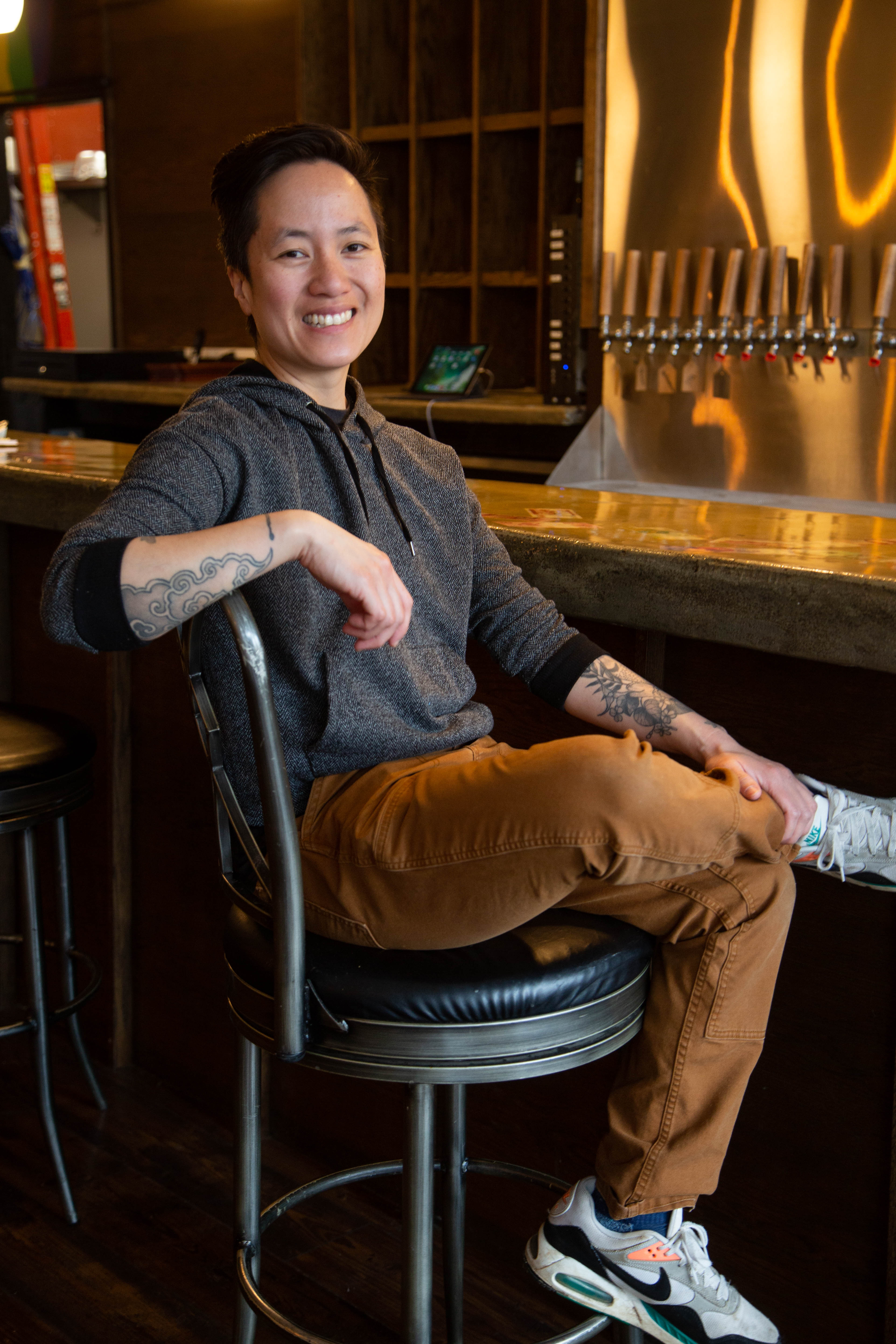A woman sits in a bar stool at a bar.