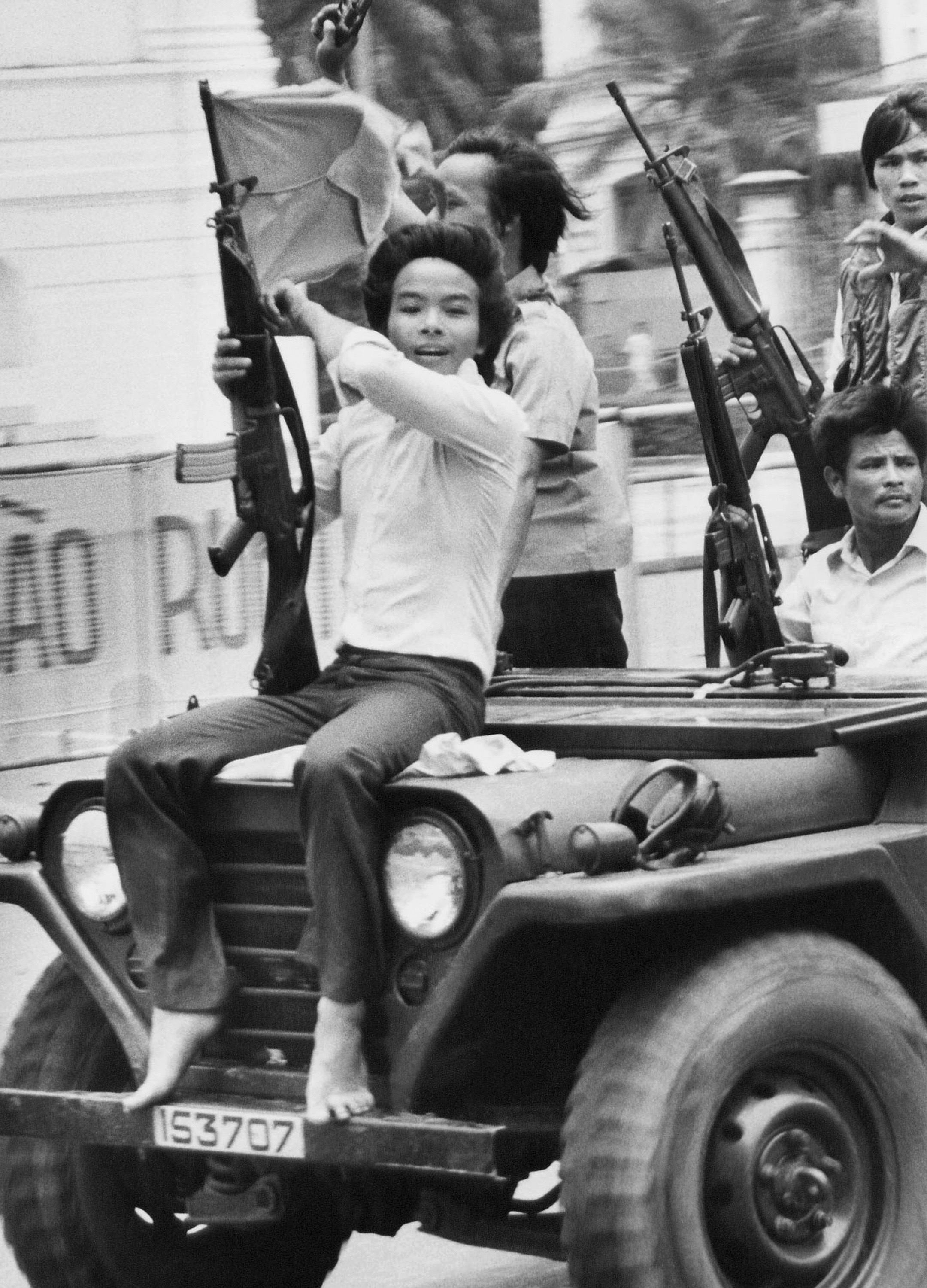In this May 4, 1975 file photo, a youth waves a weapon and a Provisional Revolutionary Government (PRG) flag as he joins PRG troops on a jeep on Tu Do street in Saigon. (AP Photo/Matt Franjola, File)