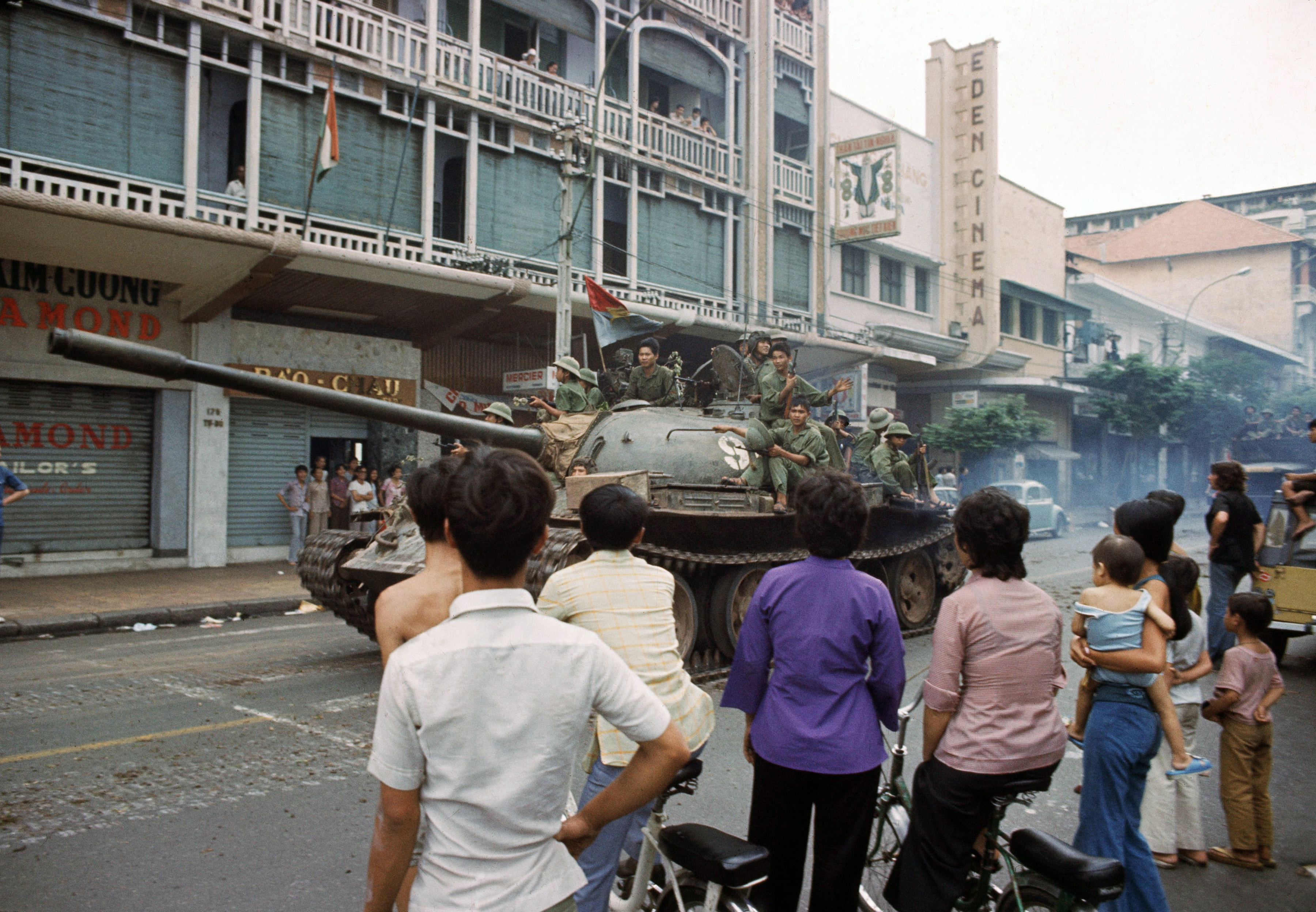 Victorious North Vietnamese troops ride a tank down Rue Catinat in Saigon while South Vietnamese civilians look on, April 30, 1975, as the capital of South Vietnam fell to communist forces, ending the Vietnam War. (AP Photo/Yves Billy)