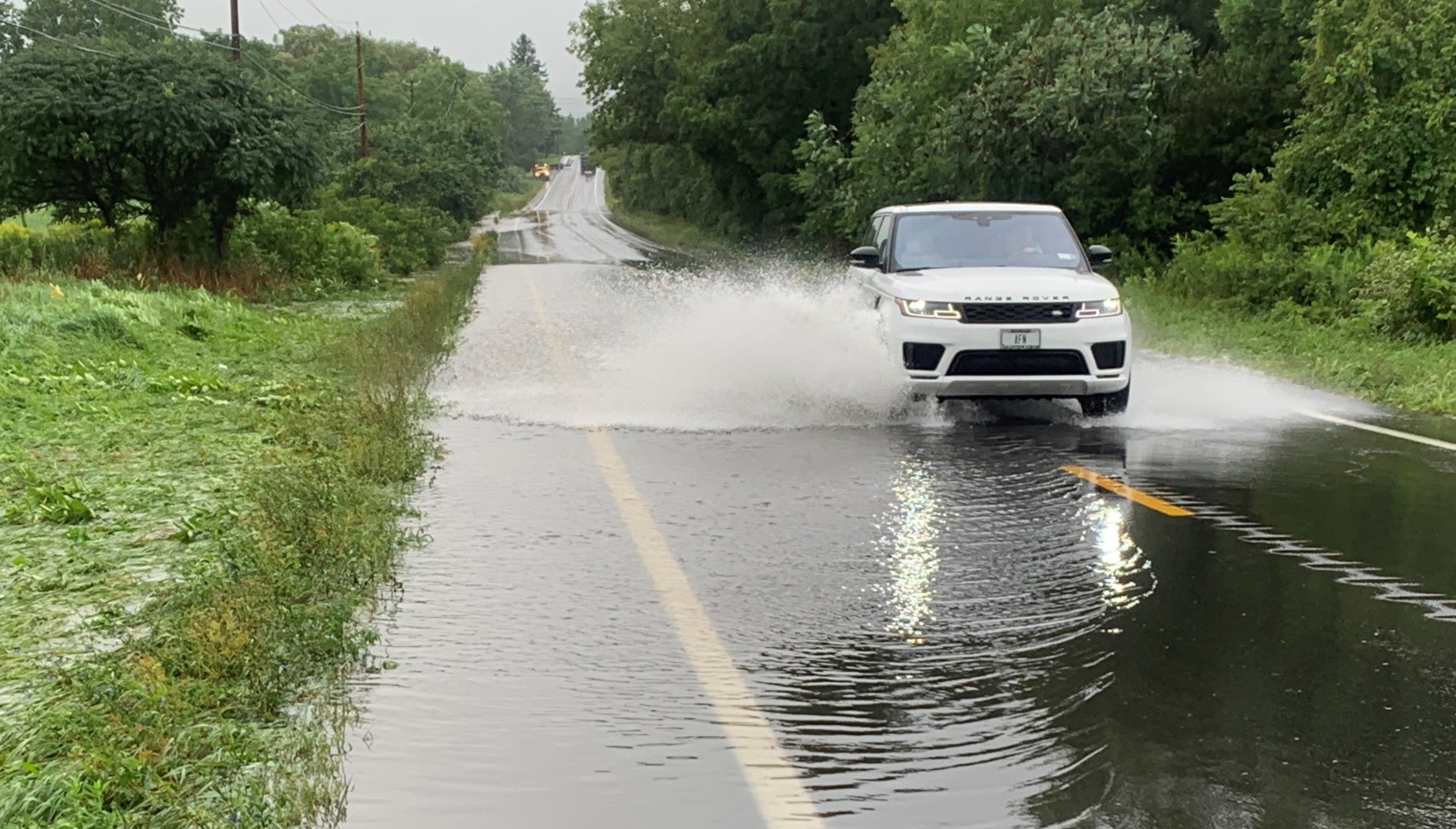 Vehicles splash through standing water along Route 321 in Skaneateles Thursday, Aug. 19, 2021.