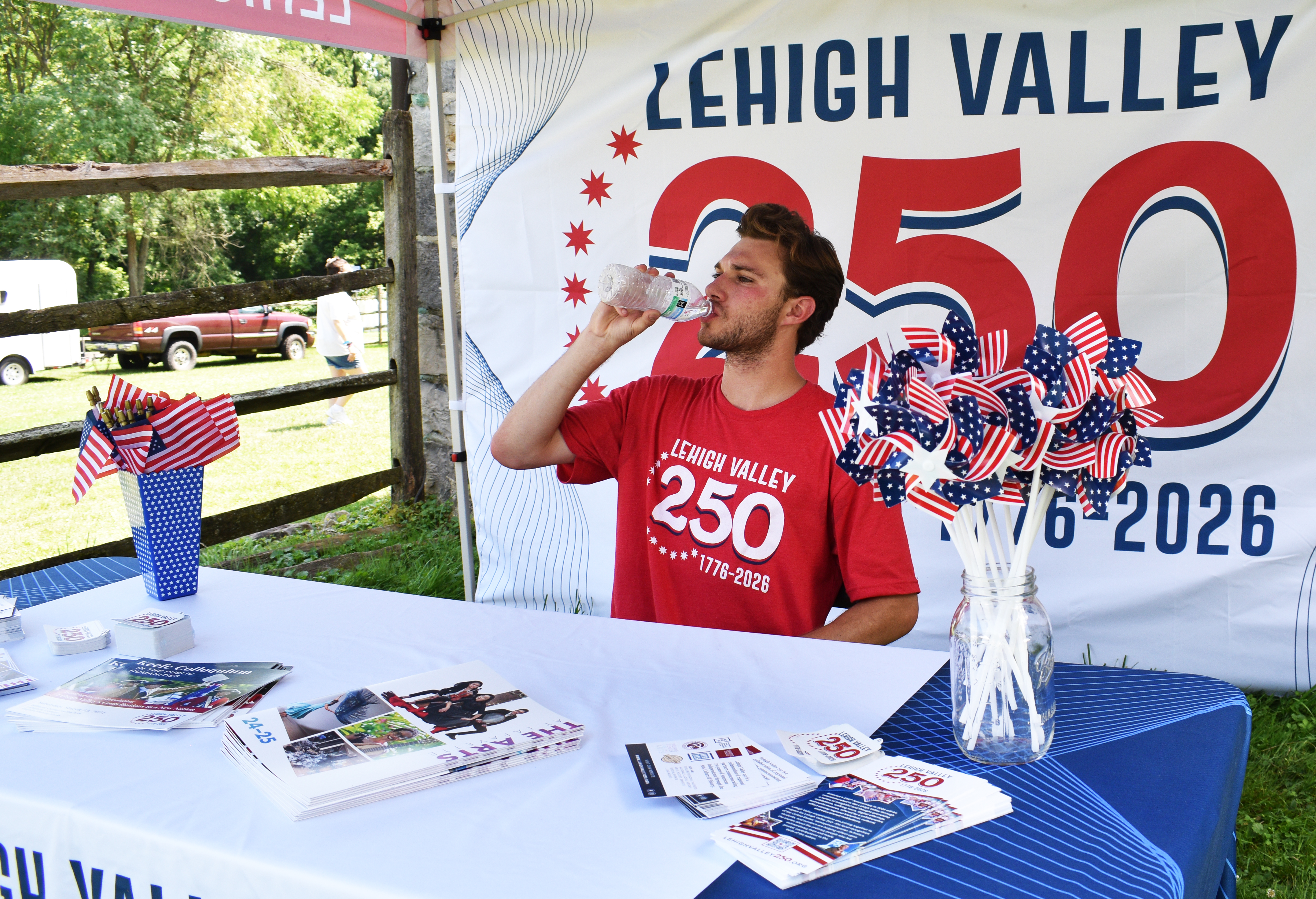 Nolan Russo from Historic Bethlehem Museums & Sites hydrates amid muggy conditions in the Lehigh Valley 250 tent ahead of the national semiquincentennial in 2026 as the nonprofit hosts the first of two days of its Blueberry Festival & Market To Go on Saturday, July 13, 2024, at Burnside Plantation.