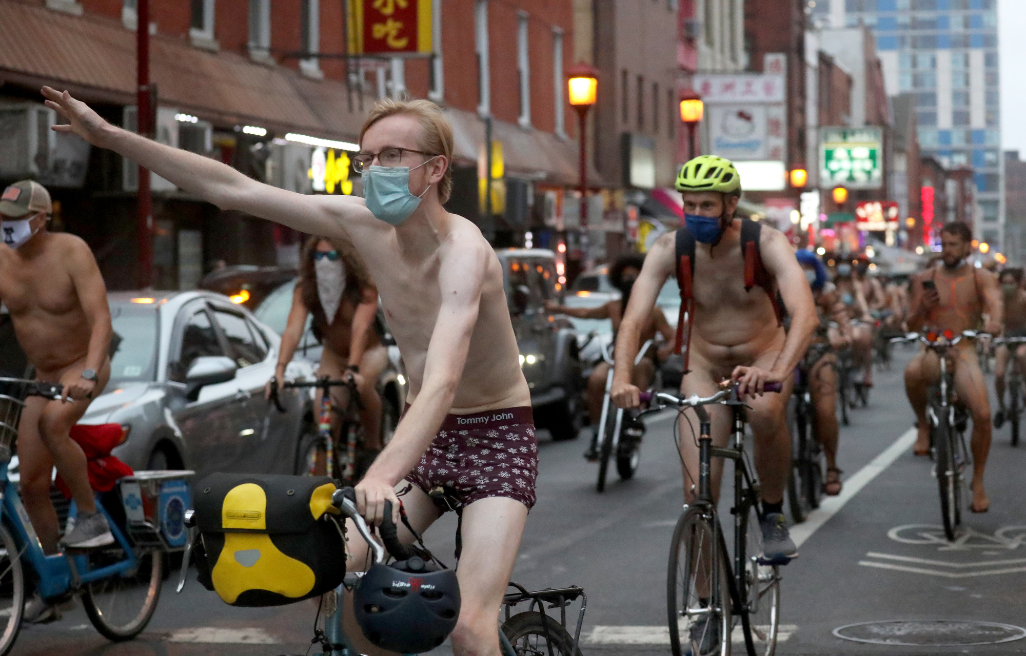 People ride bikes along 10th Street and under the Chinatown Friendship Arch in Philadelphia during the Philly Naked Bike Ride, Saturday, Aug. 28, 2021.