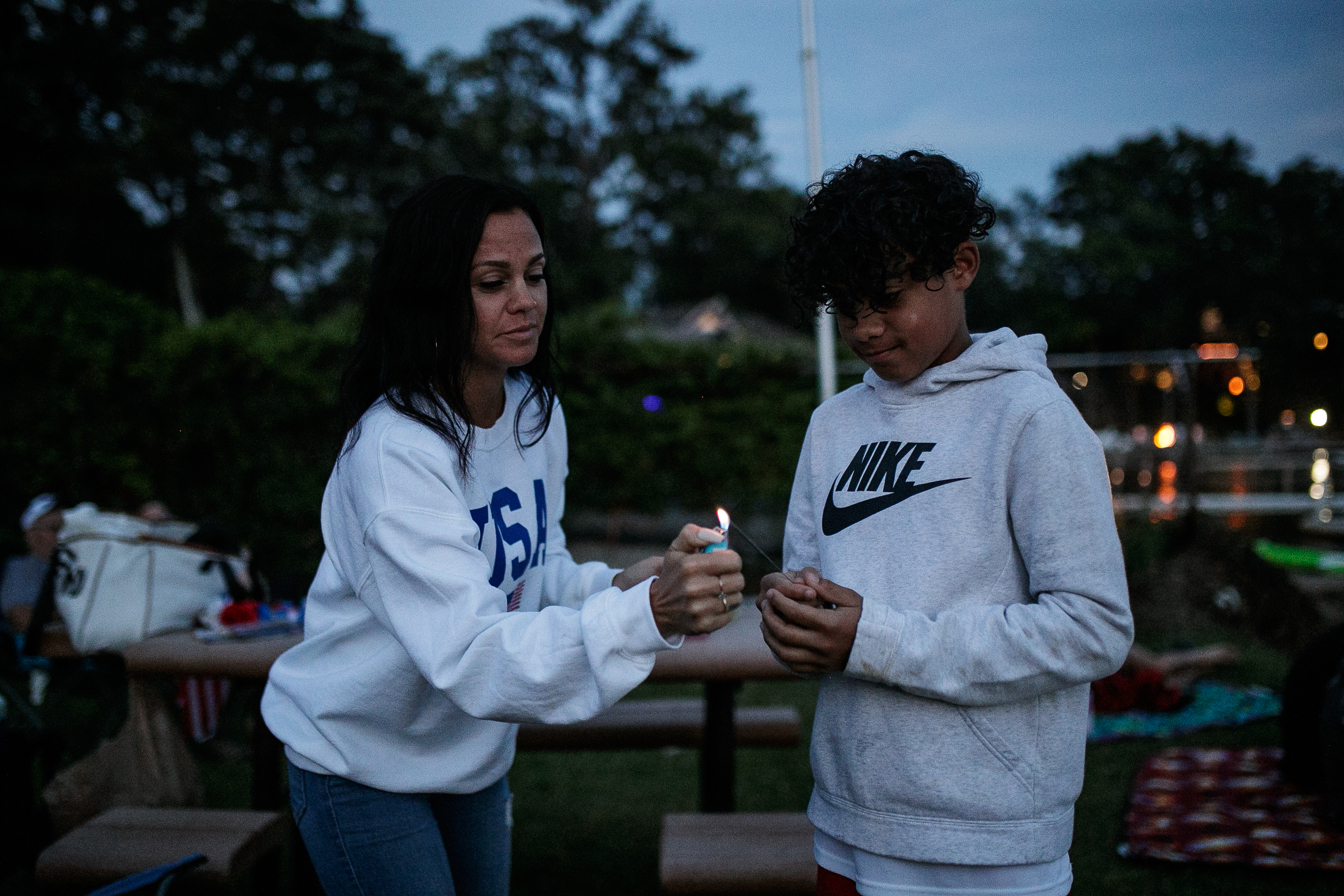 Brodi Jourdan, 10, and his mother Rachel light up a sparkler during the annual Lake Fenton Fireworks on the water in front of the Township hall on Saturday, June 2, 2022 in Fenton Township. (Jenifer Veloso | MLive.com)

