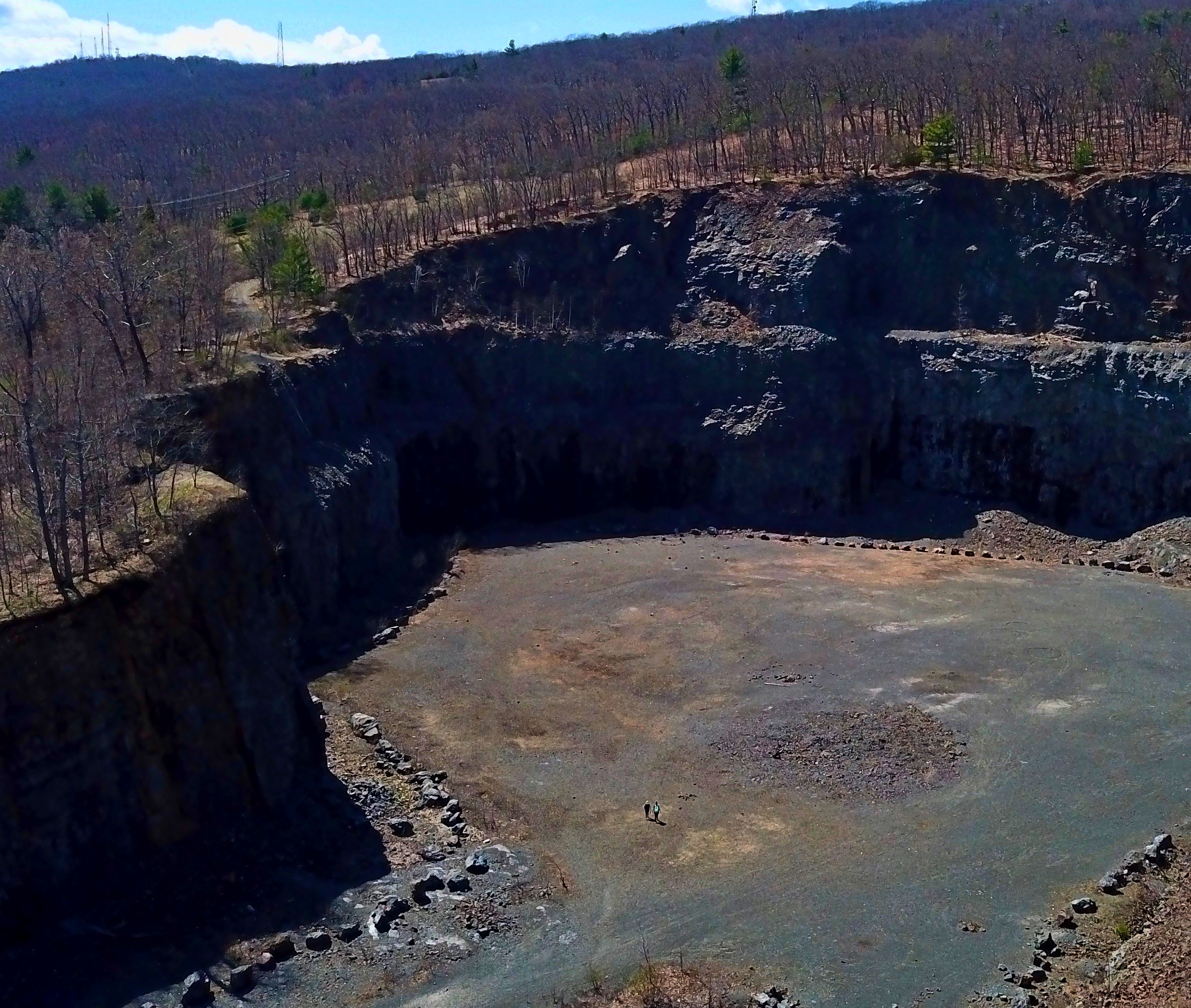 An aerial view of the quarry crater at Mt. Tom. The two hikers near the center of the photo give an idea how large the hole is.