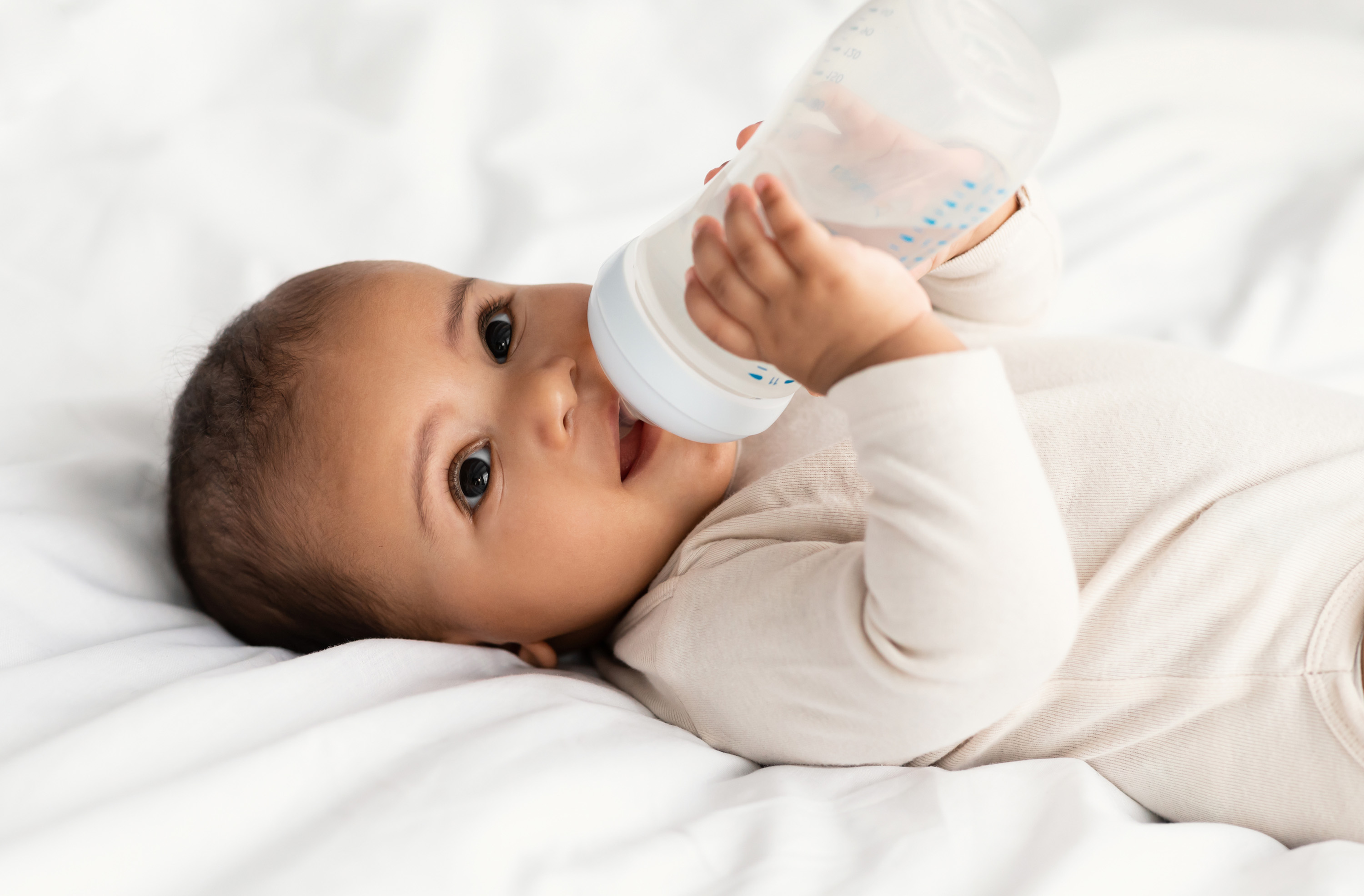 Вода для новорожденных отзывы. Малыш пьет из бутылочки. Малыш пьет из бутылочки в кроватке. Ребенок пьет из бутылочки лежа. Младенец пьет с бутылочки.