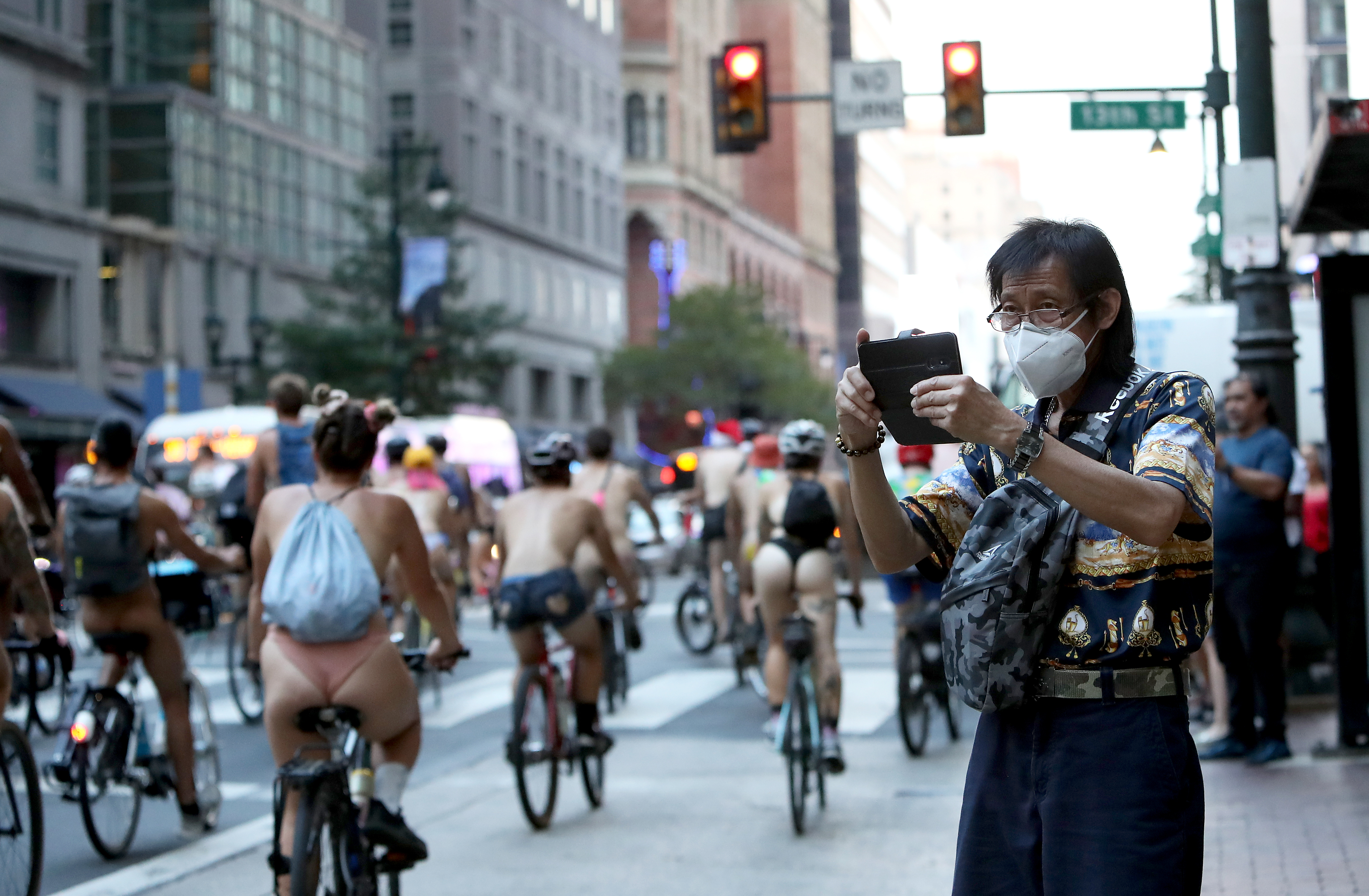 A man records as people ride bikes along Market Street in Philadelphia during the Philly Naked Bike Ride, Saturday, Aug. 27, 2022.
