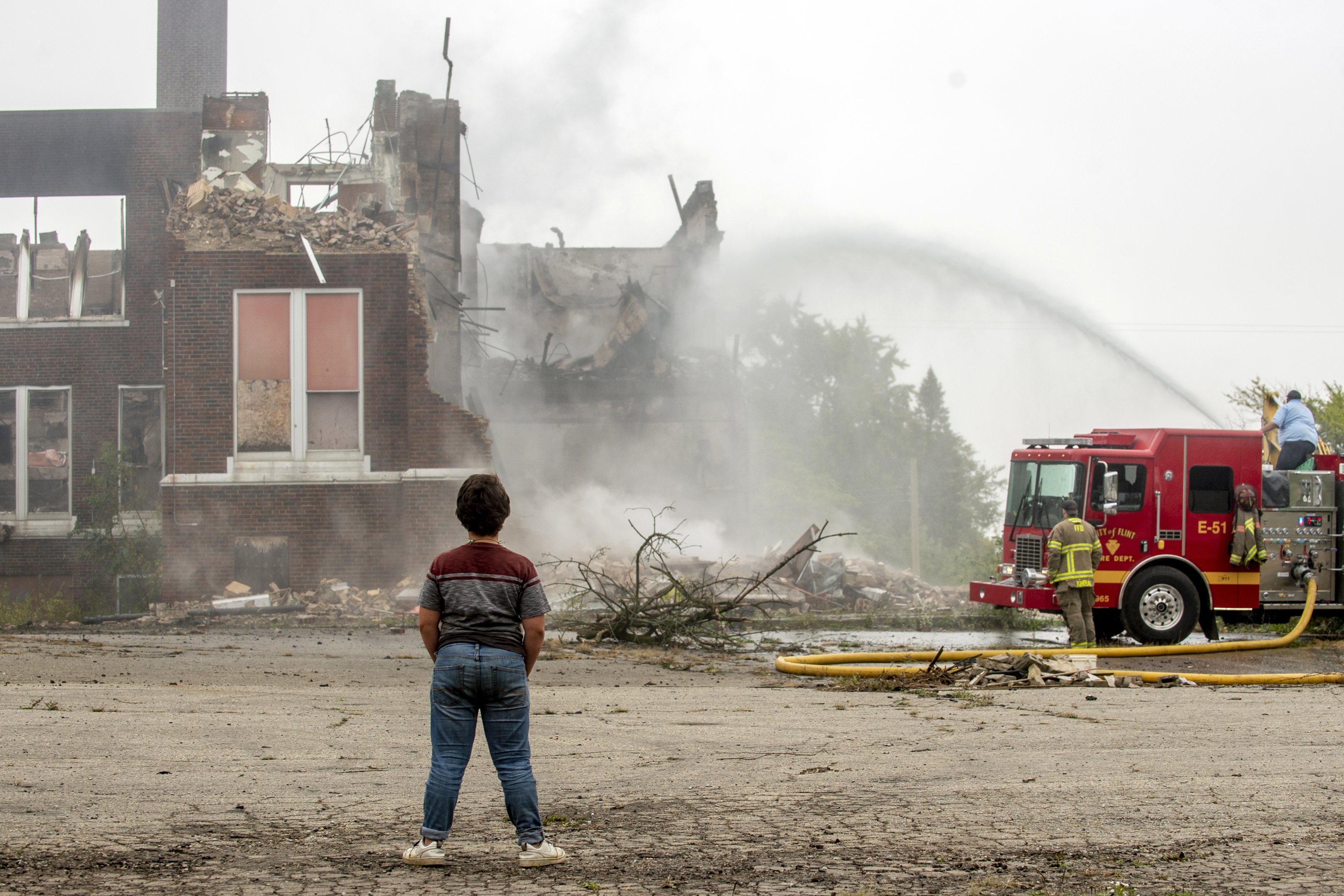 Flint residents and neighbors gather to watch the flames and smoke rise as firefighters work to contain a fire that started at about 12:30 a.m. on Thursday Oct. 7, 2021 at the former Washington Elementary School, located at 1400 N. Vernon Ave. in Flint. The building was built in 1922 before closing in 2013. (Jake May | MLive.com)