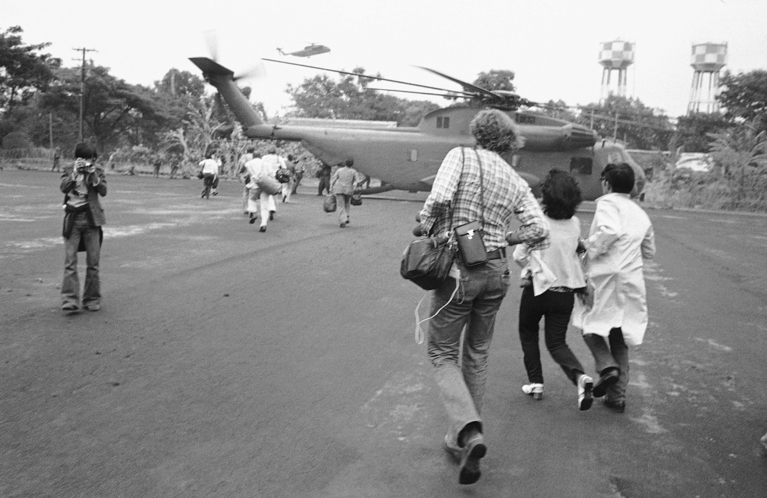 Americans and Vietnamese run for a U.S. Marine helicopter in Saigon during the evacuation of the city, April 29, 1975. (AP Photo)