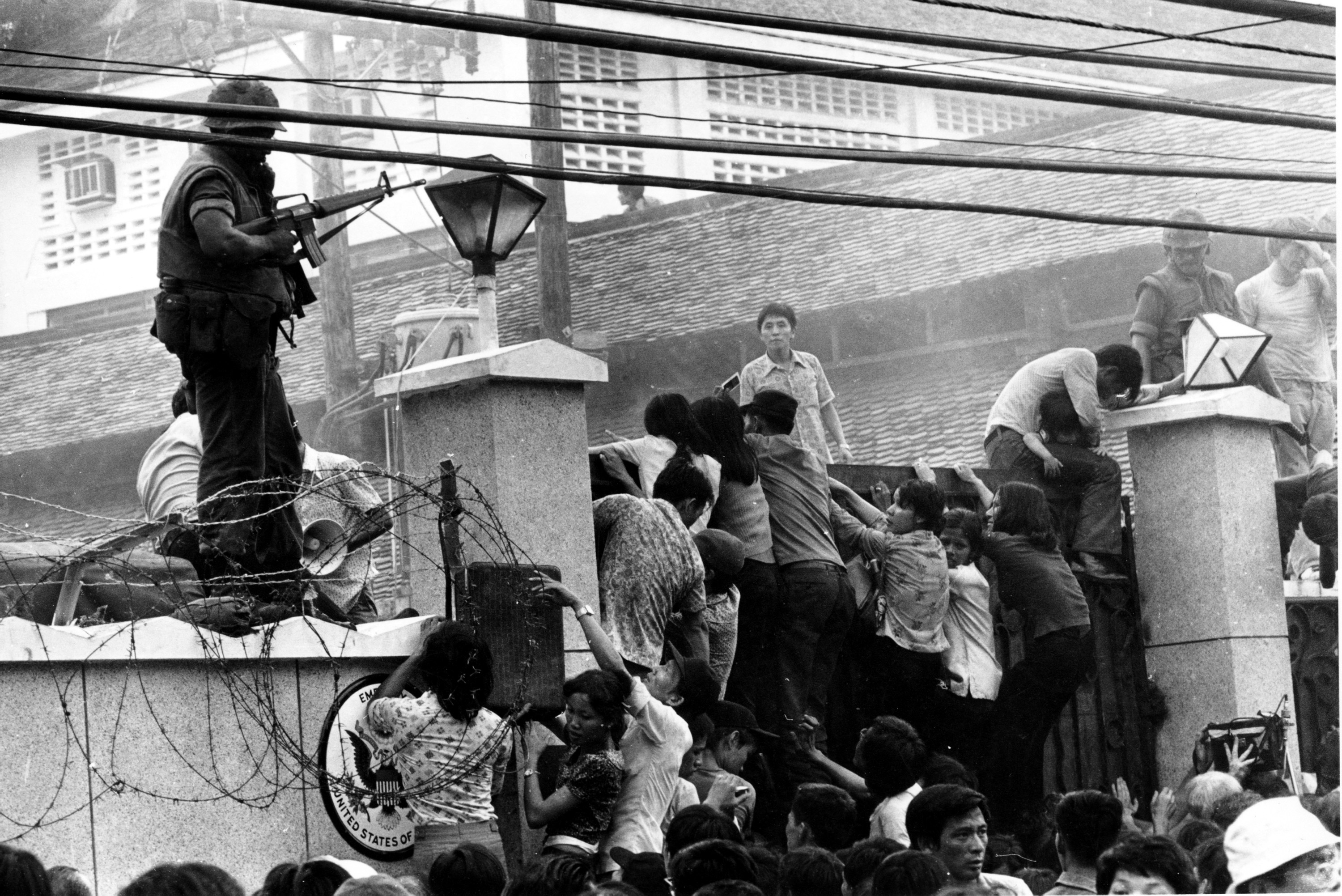 Mobs of Vietnamese people scale the wall of the U.S. Embassy in Saigon, Vietnam, trying to get to the helicopter pickup zone, just before the end of the Vietnam War on April 29, 1975.  (AP Photo/Neal Ulevich)