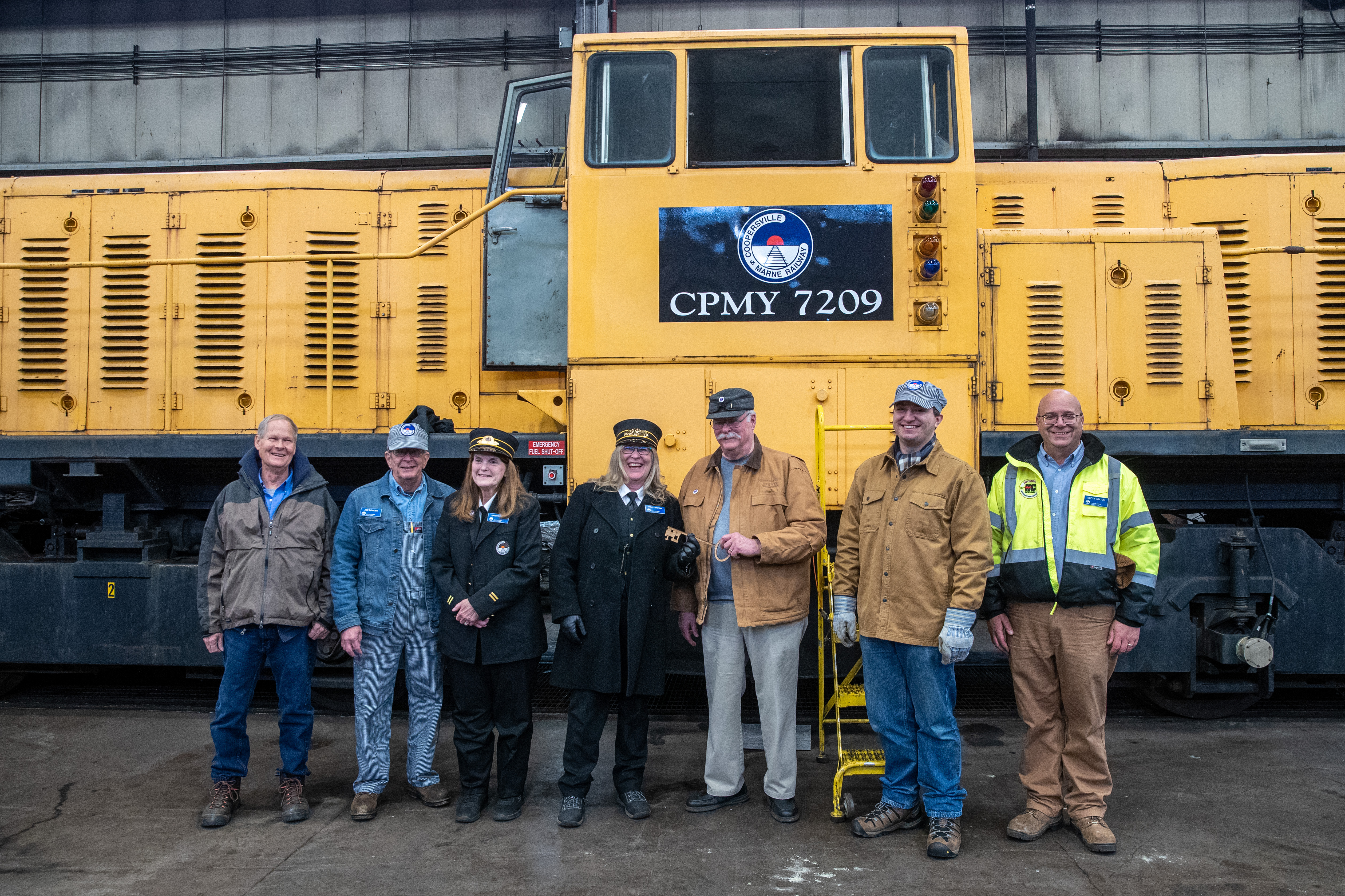 Members of the Coopersville and Marne Railway pose for a picture in front of a 1979 GE diesel train locomotive at the Consumers Energy J.H. Campbell plant in Port Sheldon Township on Monday, Feb. 13, 2023. Consumers Energy is donating the locomotive to the railway. (Cory Morse | MLive.com)