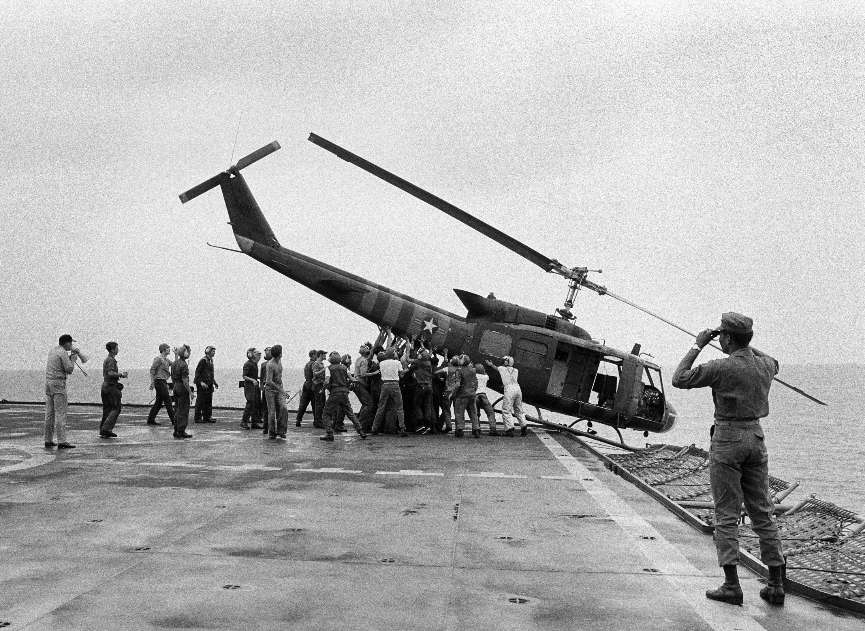 U.S. Navy personnel aboard the USS Blue Ridge push a helicopter into the sea off the coast of Vietnam in order to make room for more evacuation flights from Saigon, Tuesday, April 29, 1975.  The helicopter had carried Vietnamese fleeing Saigon as North Vietnamese forces closed in on the capitol.  (AP Photo/jt)