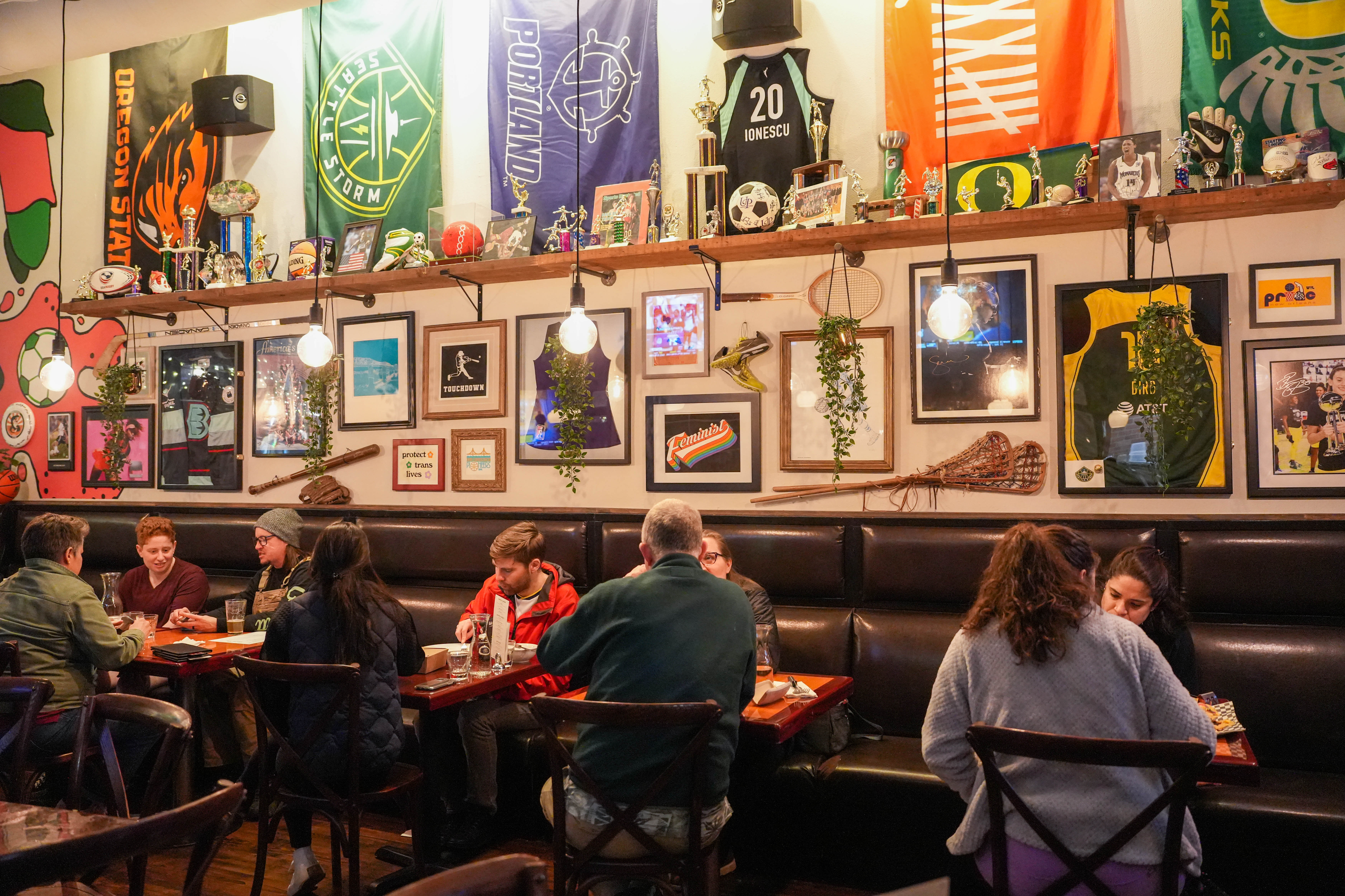 Customers dine at tables and booths with sports memorabilia on the walls