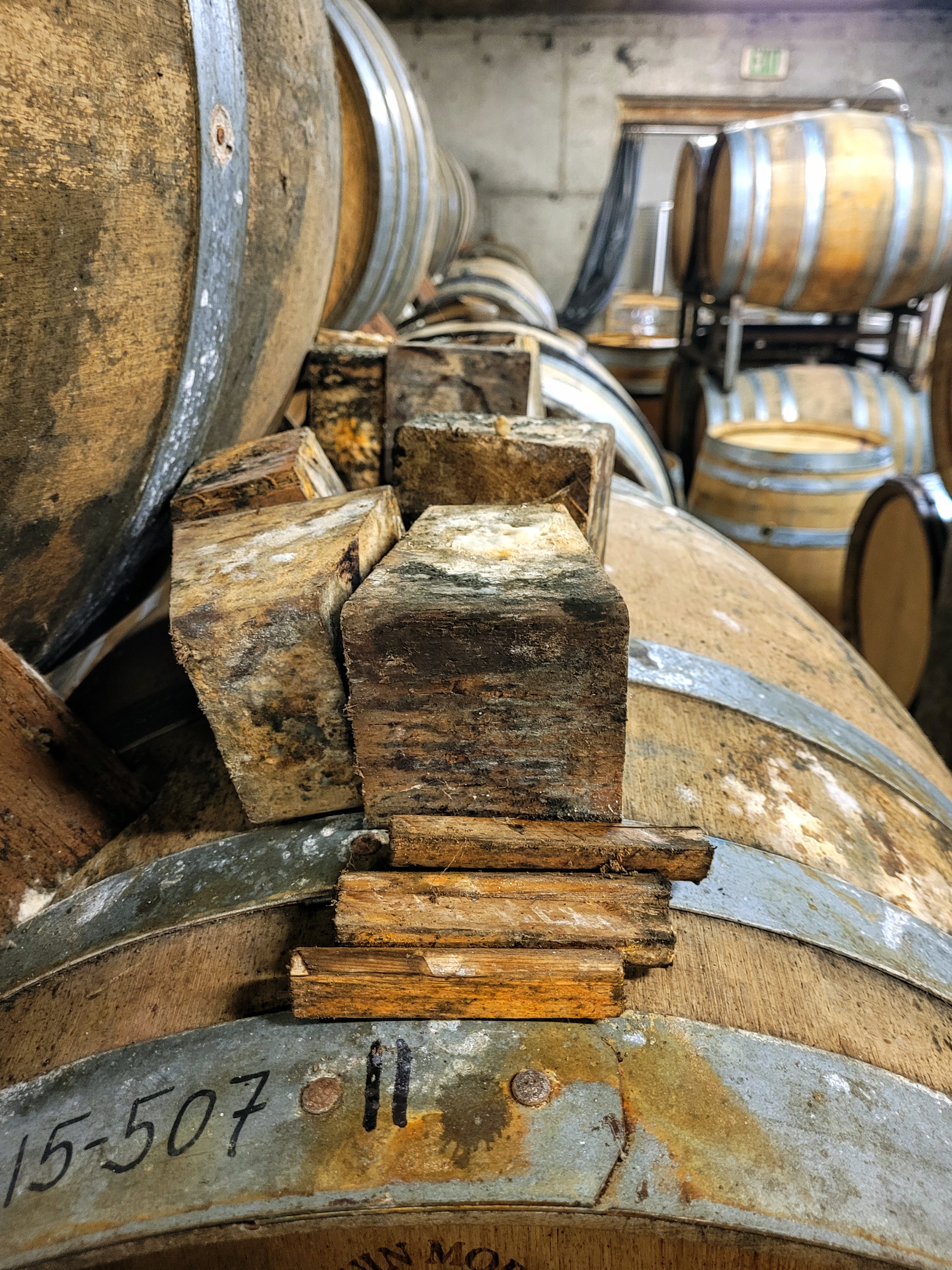 Close-up of oak wine barrels, which are supported by wooden blocks.