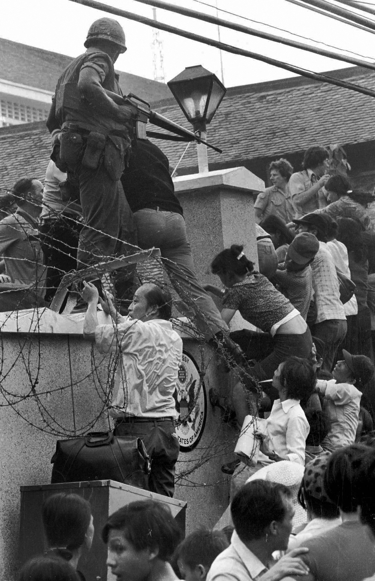 FILE - In this April 29, 1975 file photo, people try to scale the 14-foot wall of the U.S. embassy in Saigon, trying to reach evacuation helicopters, as the last of the Americans depart from Vietnam. (AP Photo/Neal Ulevich, File)