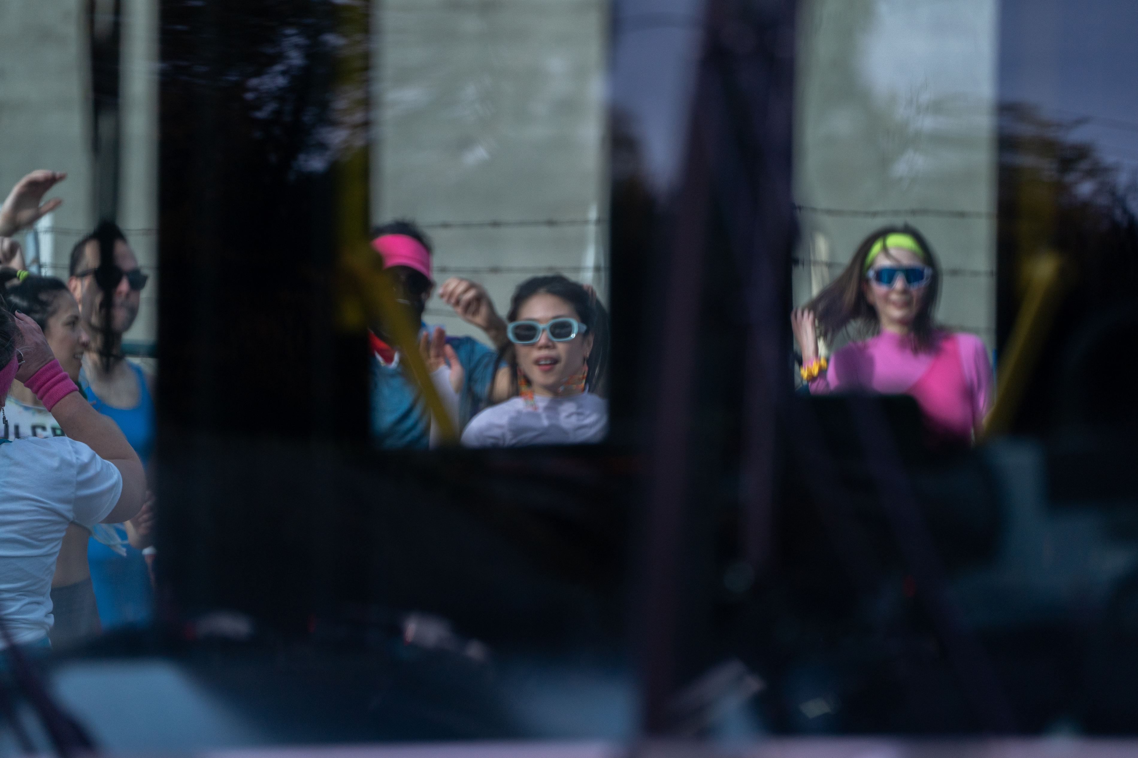 Participants in Fulcrum Fitness’s “Sweatin’ Out the Fascists” workout can be seen through a passing TriMet Bus outside the U.S. Immigration and Customs Enforcement (ICE) facility in South Portland on Sunday, Nov. 9, 2025. The gorup was collecting donations for the Oregon Food Bank.
