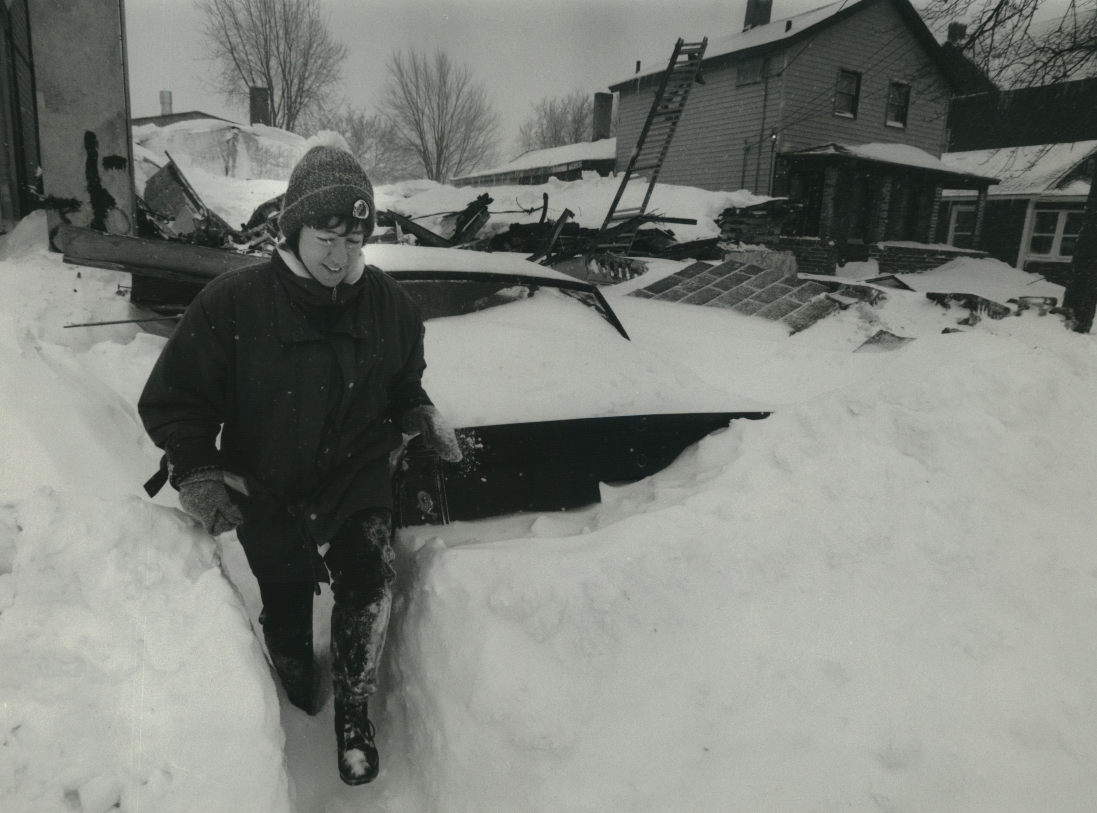 Post-Standard Reporter Jackie Arnold going through snow banks after interviewing people about building collapse in the background at 308 Marcellus Street, Syracuse.