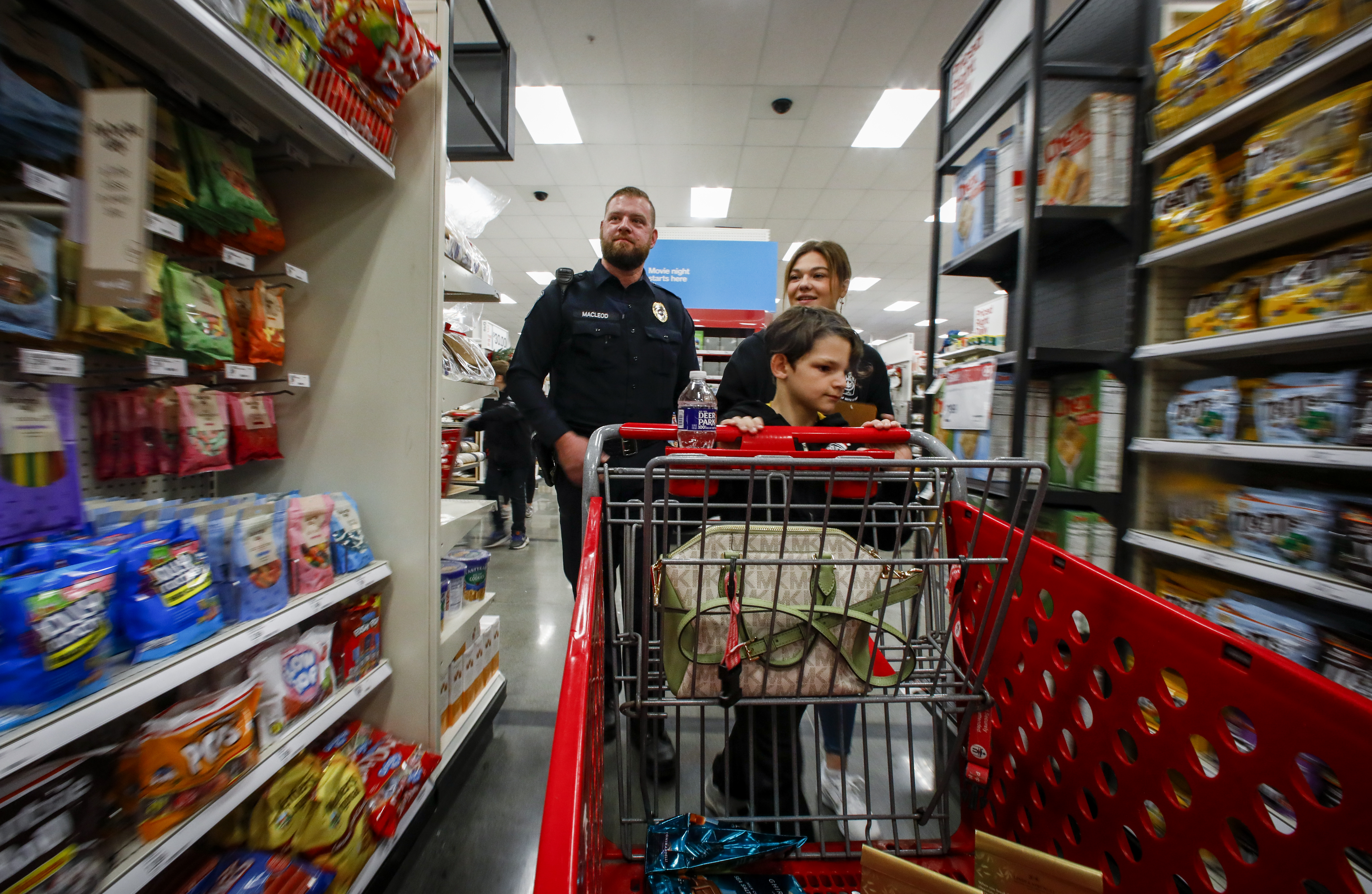 Officer Ian Macleod and Teacher Marlaina Riegel follow Jacob Thompson, 10, around Target in Hanover Township on Saturday, Dec. 3, 2022, during a holiday shopping spree. 