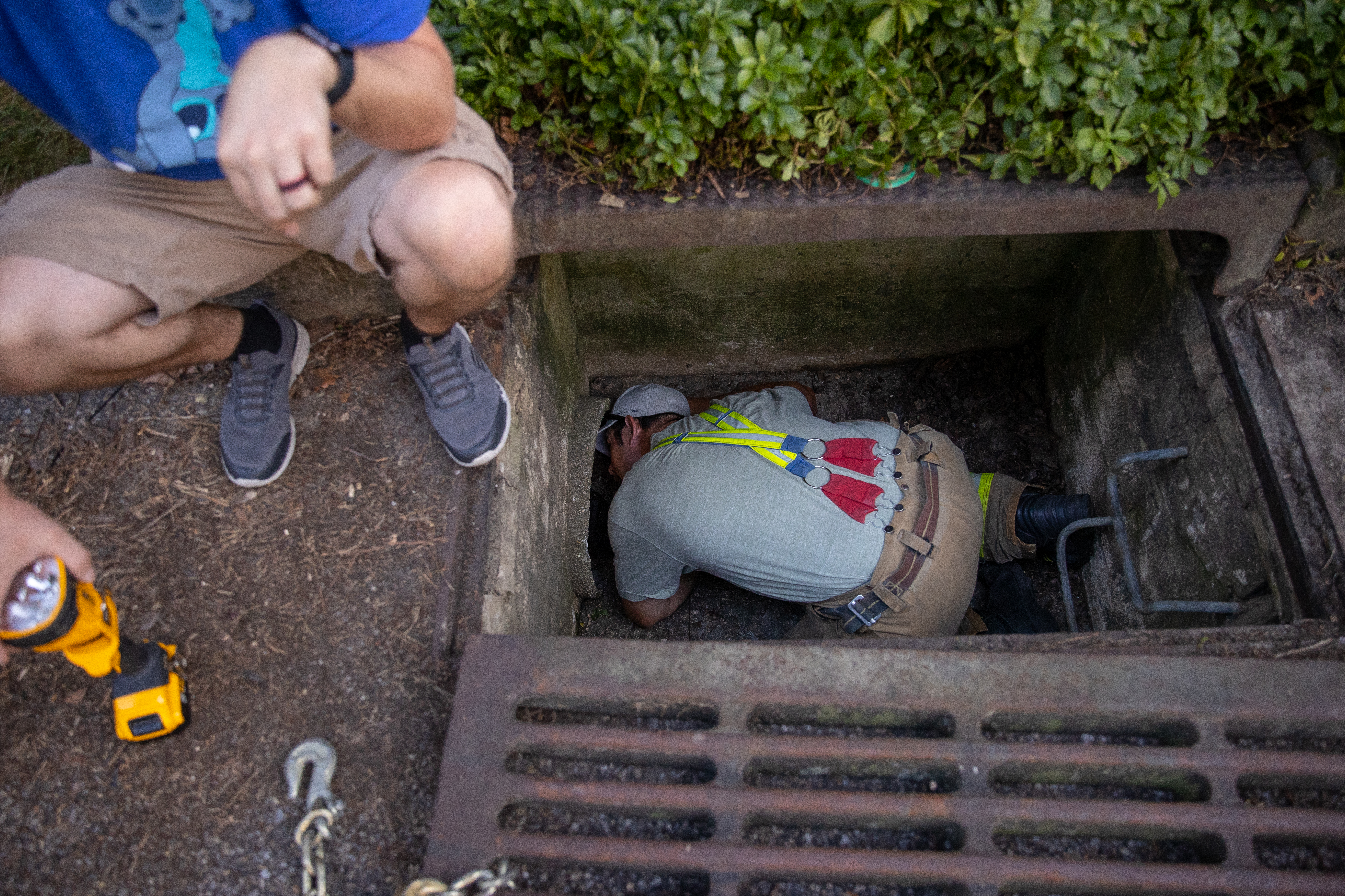 Medford Fire Lieutenant Chris Rabbuttino looks down a drain pipe in Medford, NJ on Saturday, July 23, 2022.  Dylan, an 8 year old coonhound lost for a week, was located 140-150 feet into an 18 inch drain pipe.