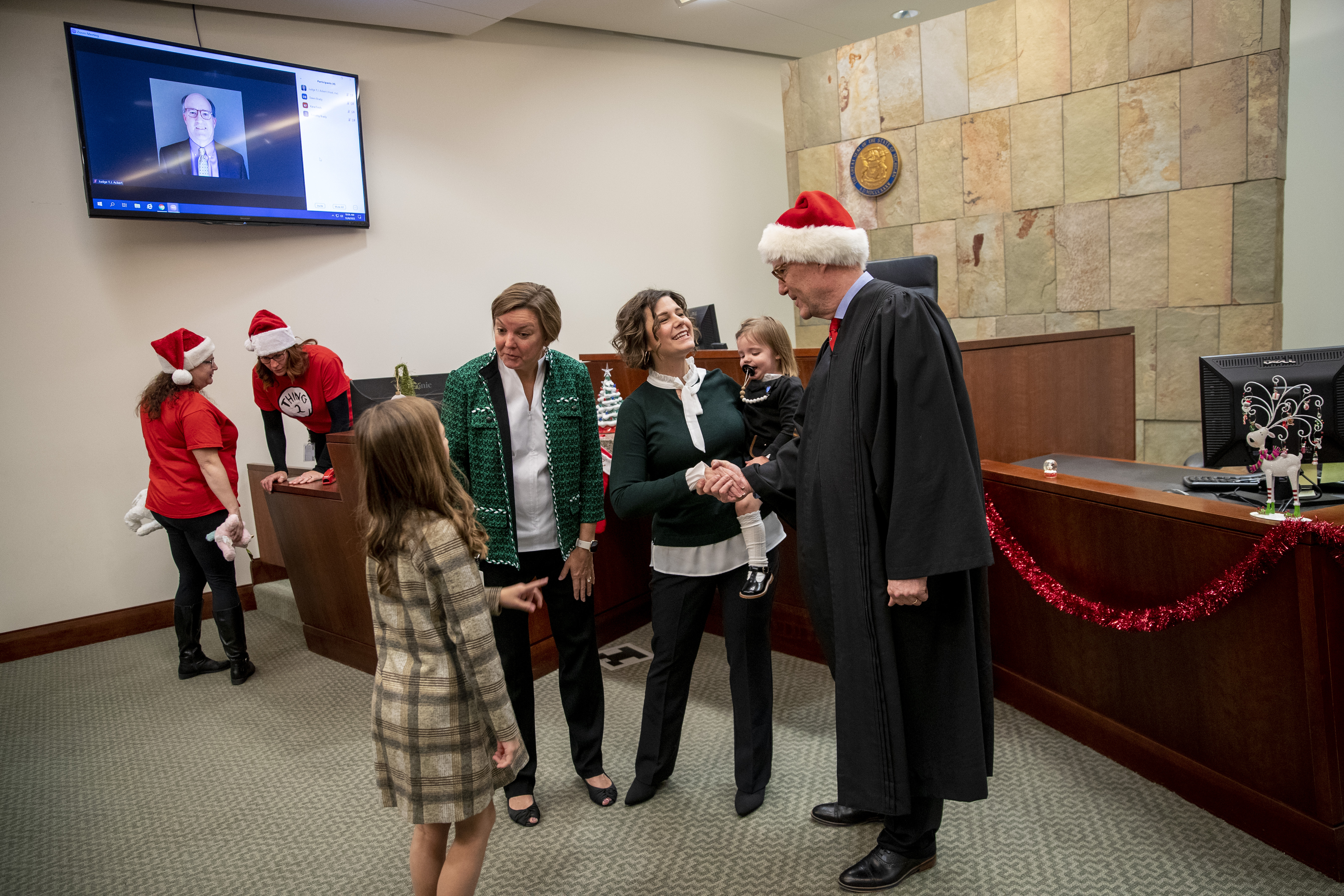 Judge T.J. Ackert, right, talks with Tammy Myers while preparing to pose for pictures during Adoption Day at the Kent County Courthouse in Grand Rapids on Thursday, Dec. 8, 2022. Tammy and Jordan Myers are the biological parents of 1-year-old twins Eames and Ellison. Lauren Vermilye, a surrogate, gave birth to the twins after Tammy went through breast cancer treatment and has no claim to the babies. The Myers family was able to adopt the twins after convincing the court system to grant them custody. (Cory Morse | MLive.com)