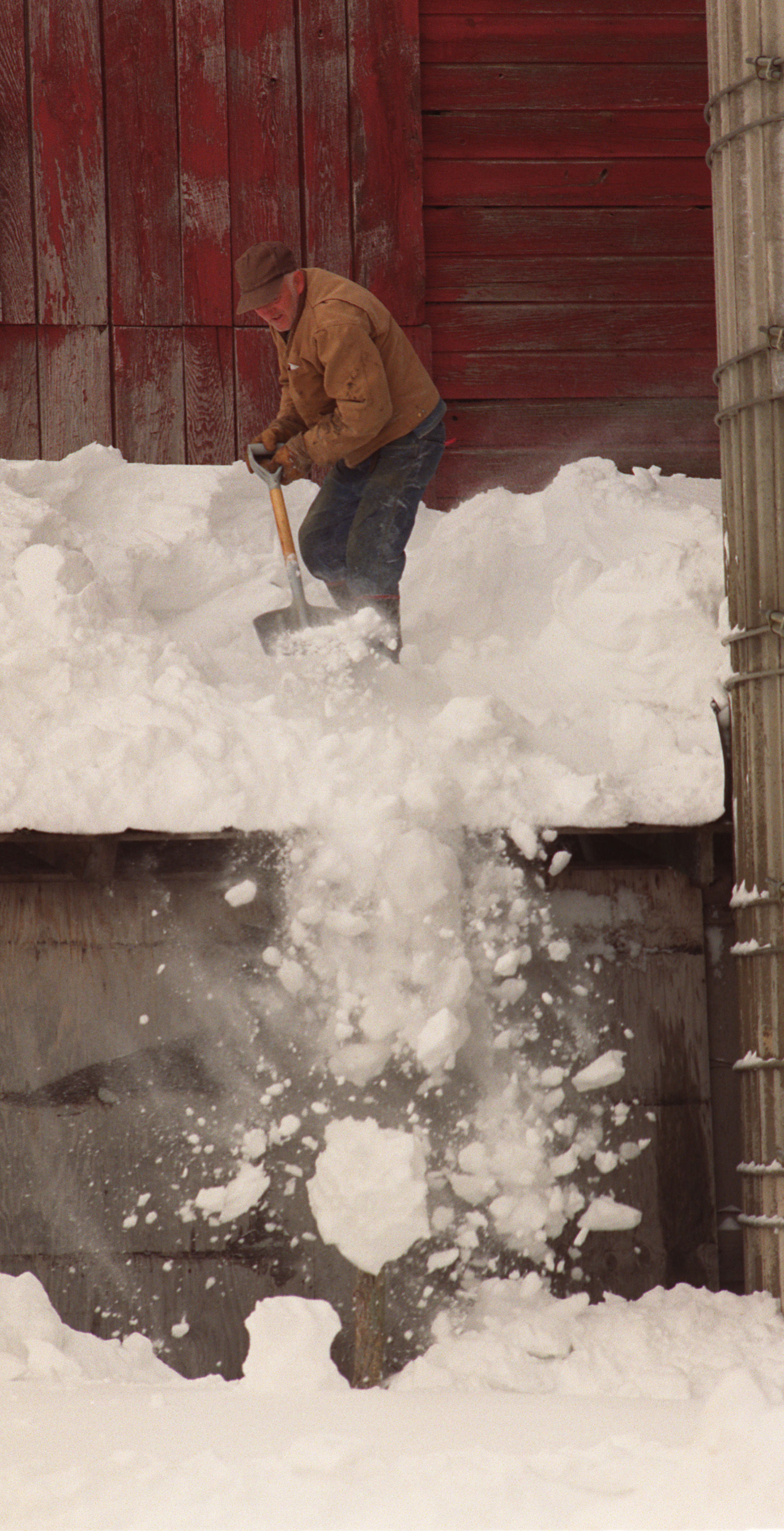 A farmer shovels snow off his barn roof in Otselic, Madison County on March 16, 1993.