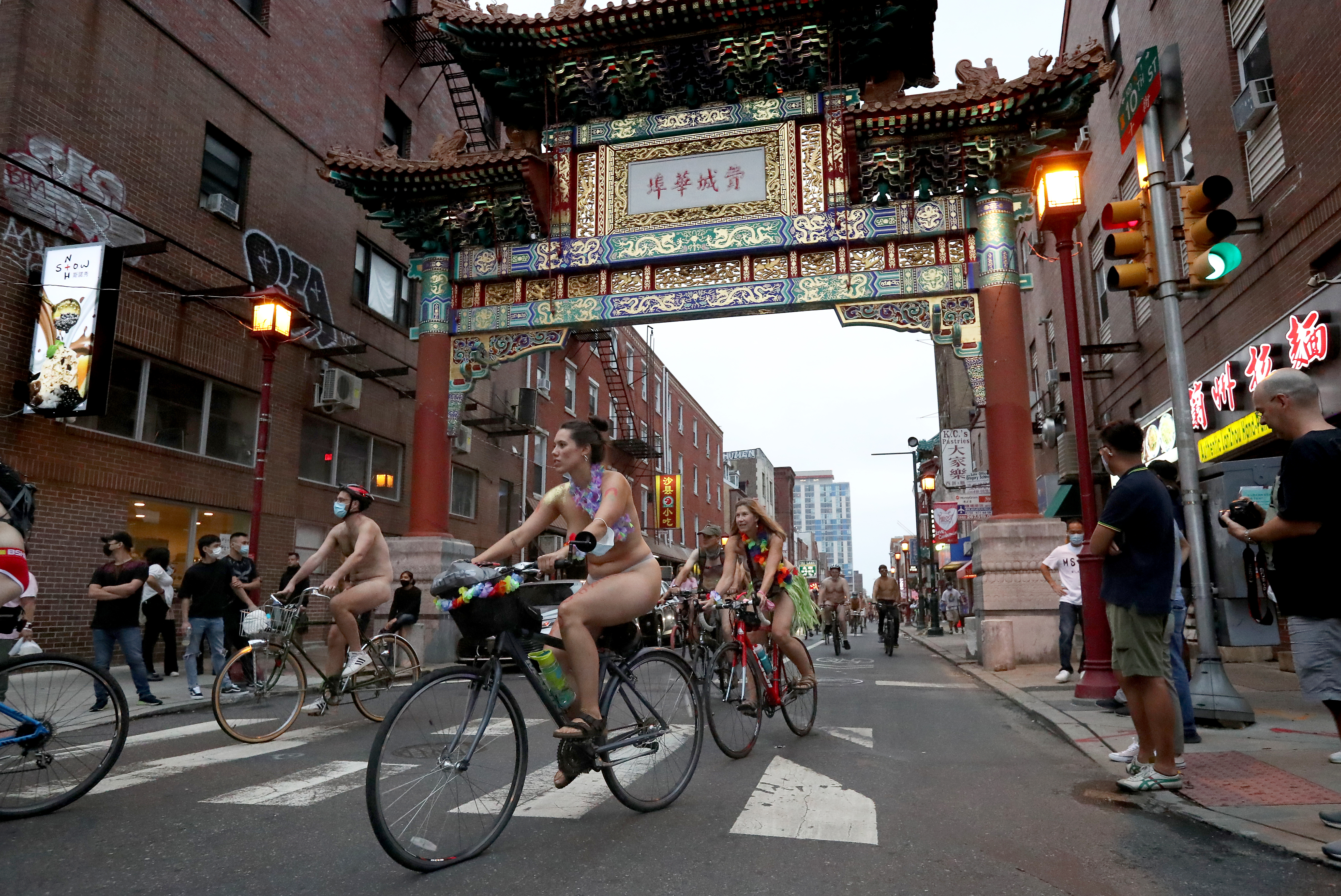 People ride bikes along 10th Street and under the Chinatown Friendship Arch in Philadelphia during the Philly Naked Bike Ride, Saturday, Aug. 28, 2021.