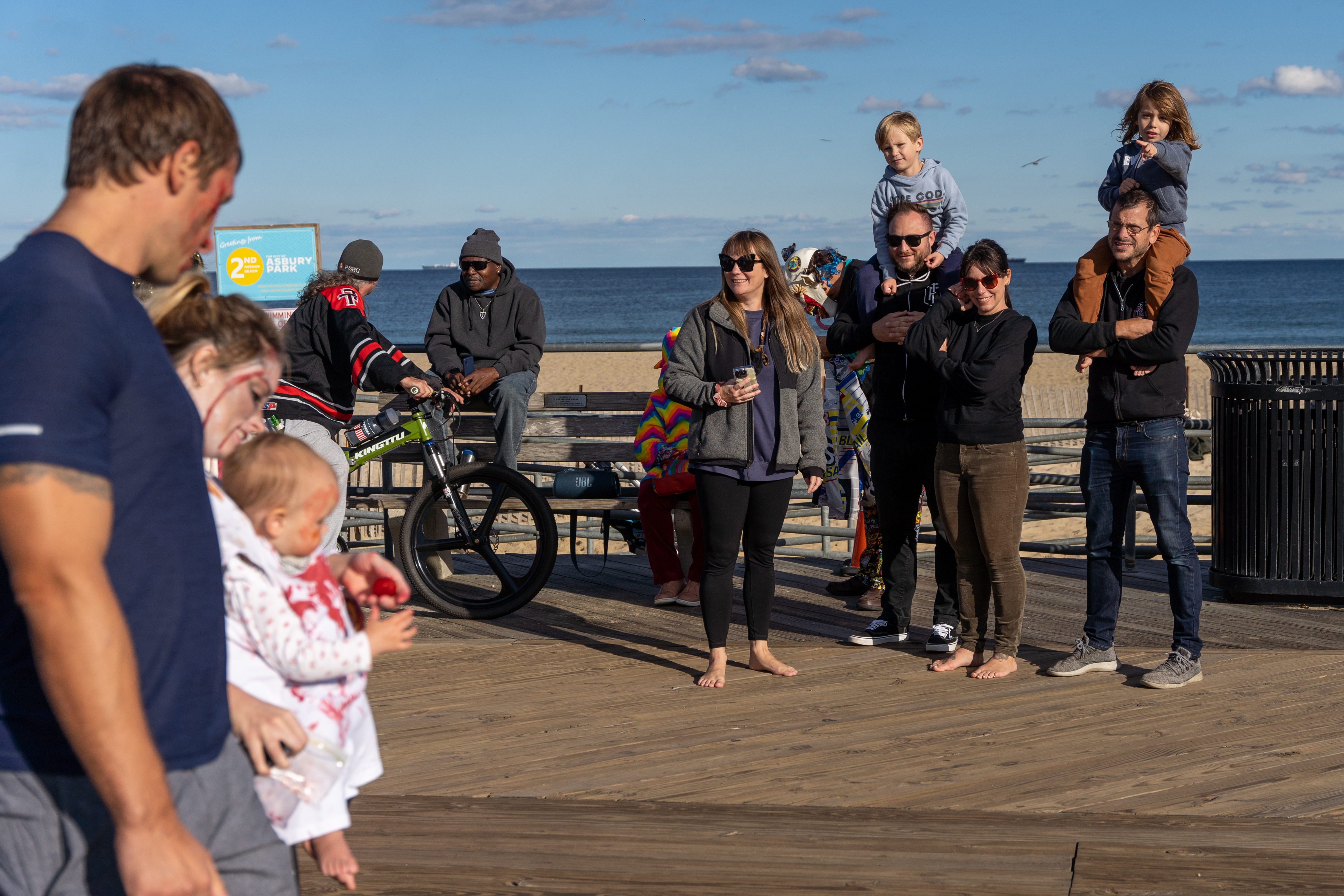 A family on the boardwalk watches a zombie family pass by during the 14th Asbury Park Zombie Walk in Asbury Park on Saturday, October 8, 2022. The zombie walk held its first themed year with the theme being 80's and 90's punk and metal.