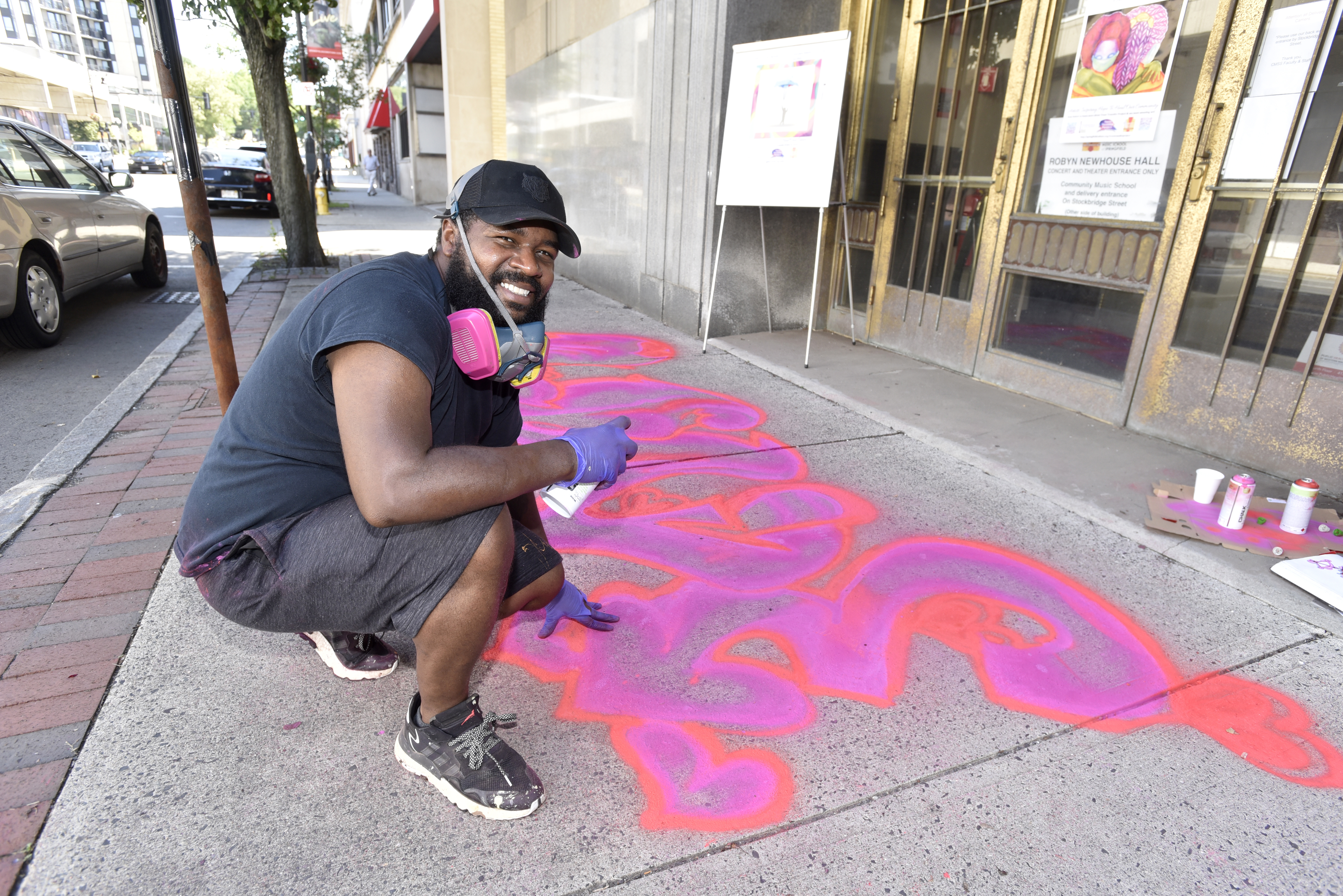 Artist Marc Austin of Springfield with his aerosol chalk creation, ""Love"", on the sidewalk in front of the Community Music School on State Street. This is part of the Trust Transfer Project's "Chalk for Change" initiative that created street art in various locations in downtown Springfield.  (Don Treeger / The Republican)  6/30/2021