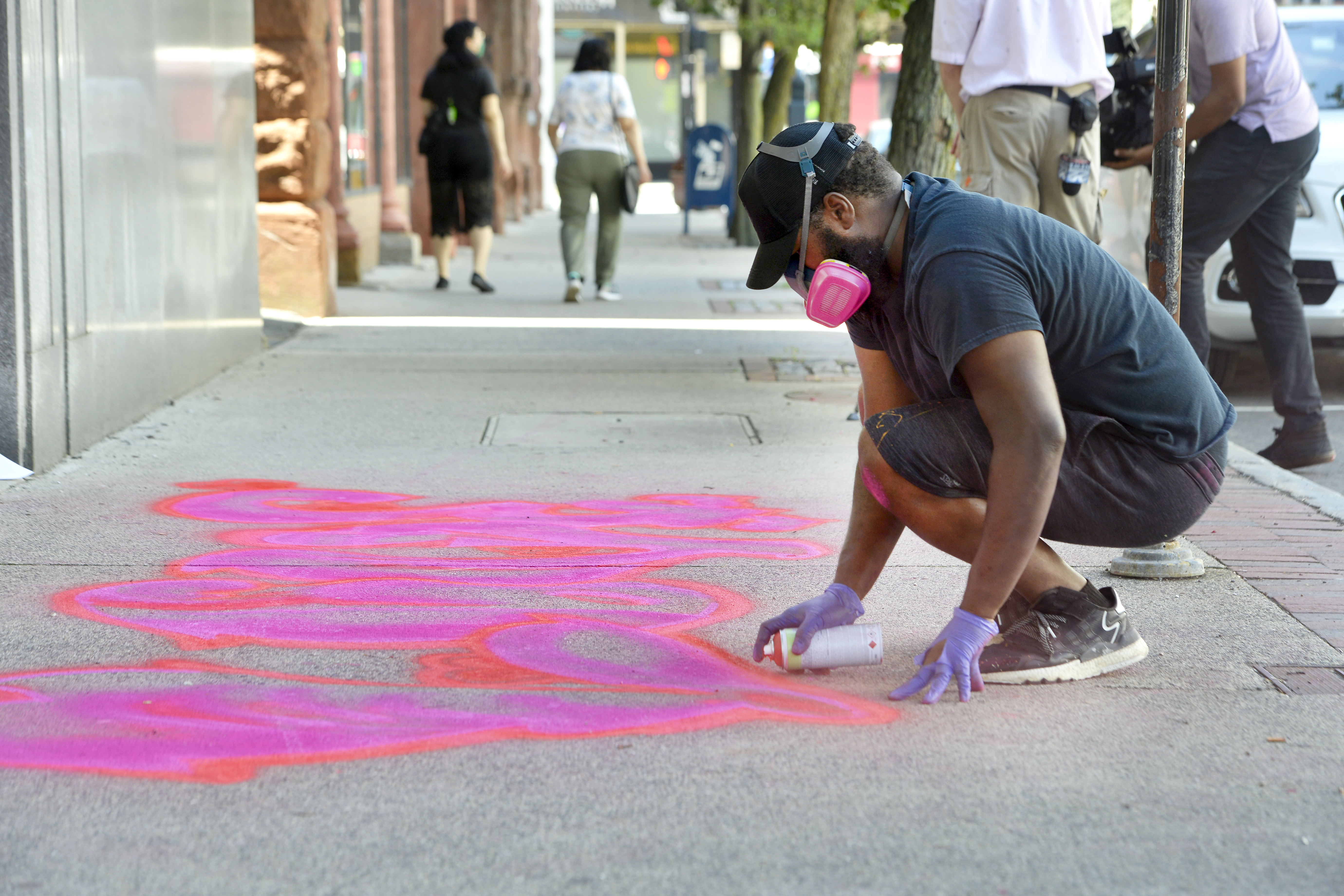 Artist Marc Austin of Springfield works on his aerosol chalk creation, ""Love"", on the sidewalk in front of the Community Music School on State Street. This is part of the Trust Transfer Project's "Chalk for Change" initiative that created street art in various locations in downtown Springfield.  (Don Treeger / The Republican)  6/30/2021