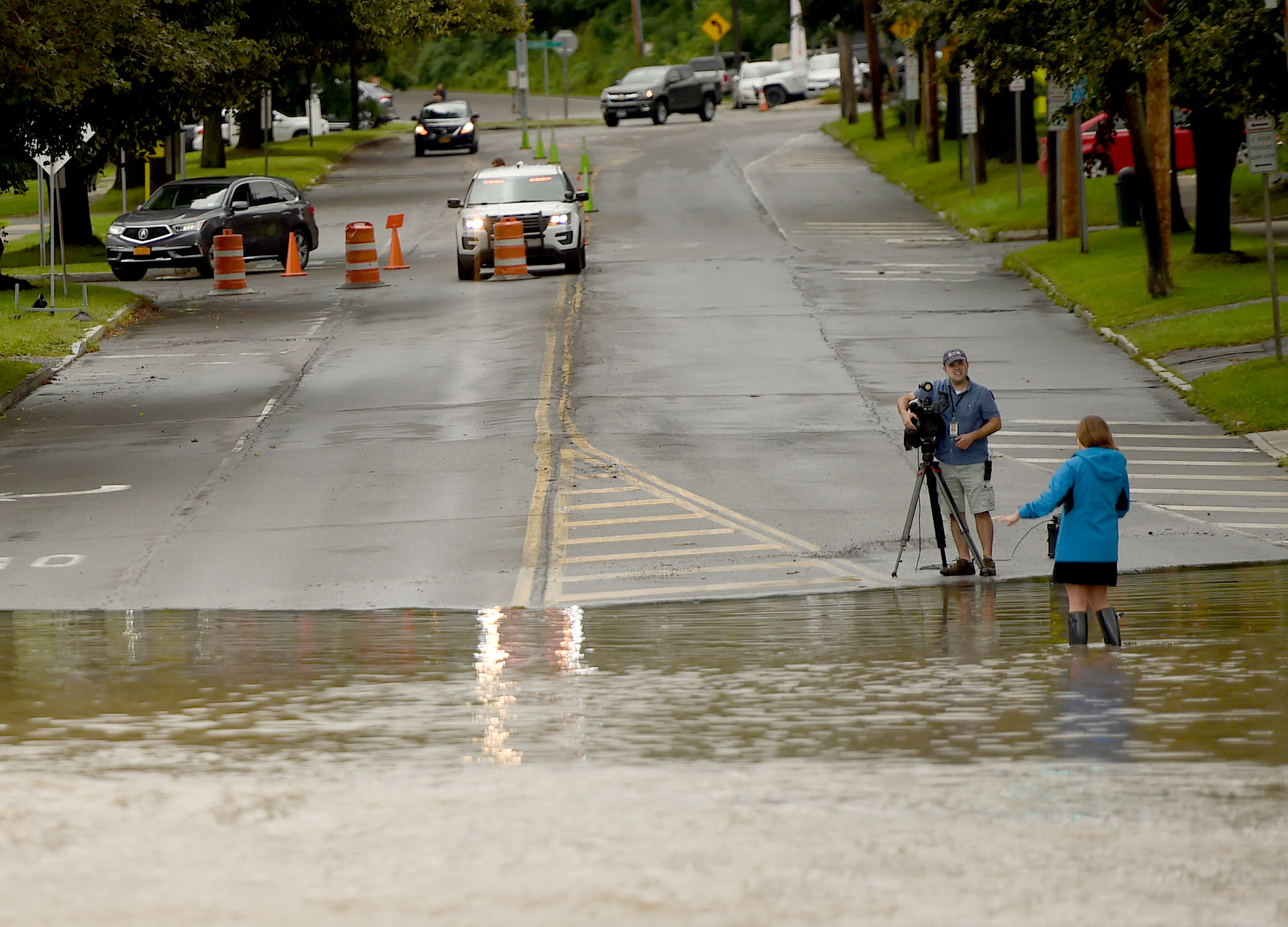 A  television crew tells their story on Genesee Street in Camillus August 19, 2021. Heavy rains again created flooding in Central New York. A lot of flooding occurred along Ninemile Creek in Camillus and Marcellus. Dennis Nett | dnett@syracuse.com