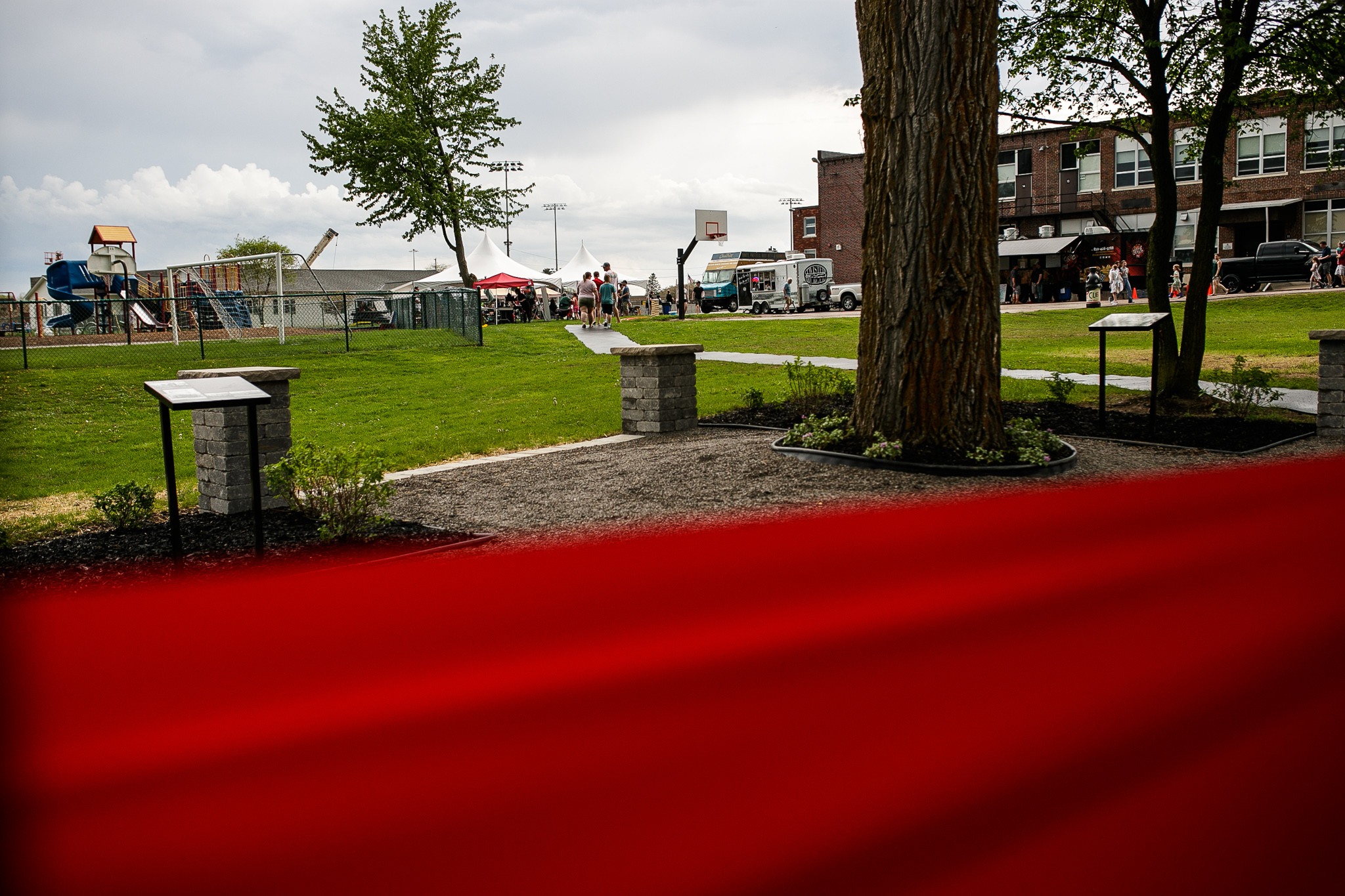 From behind the red ribbon on the new Perry Centennial Pavilion, event attendants can be seeing waiting in line for activities during the Perry Center Centennial Event in Grand Blanc on Saturday, May 14, 2022. (Jenifer Veloso | MLive.com)