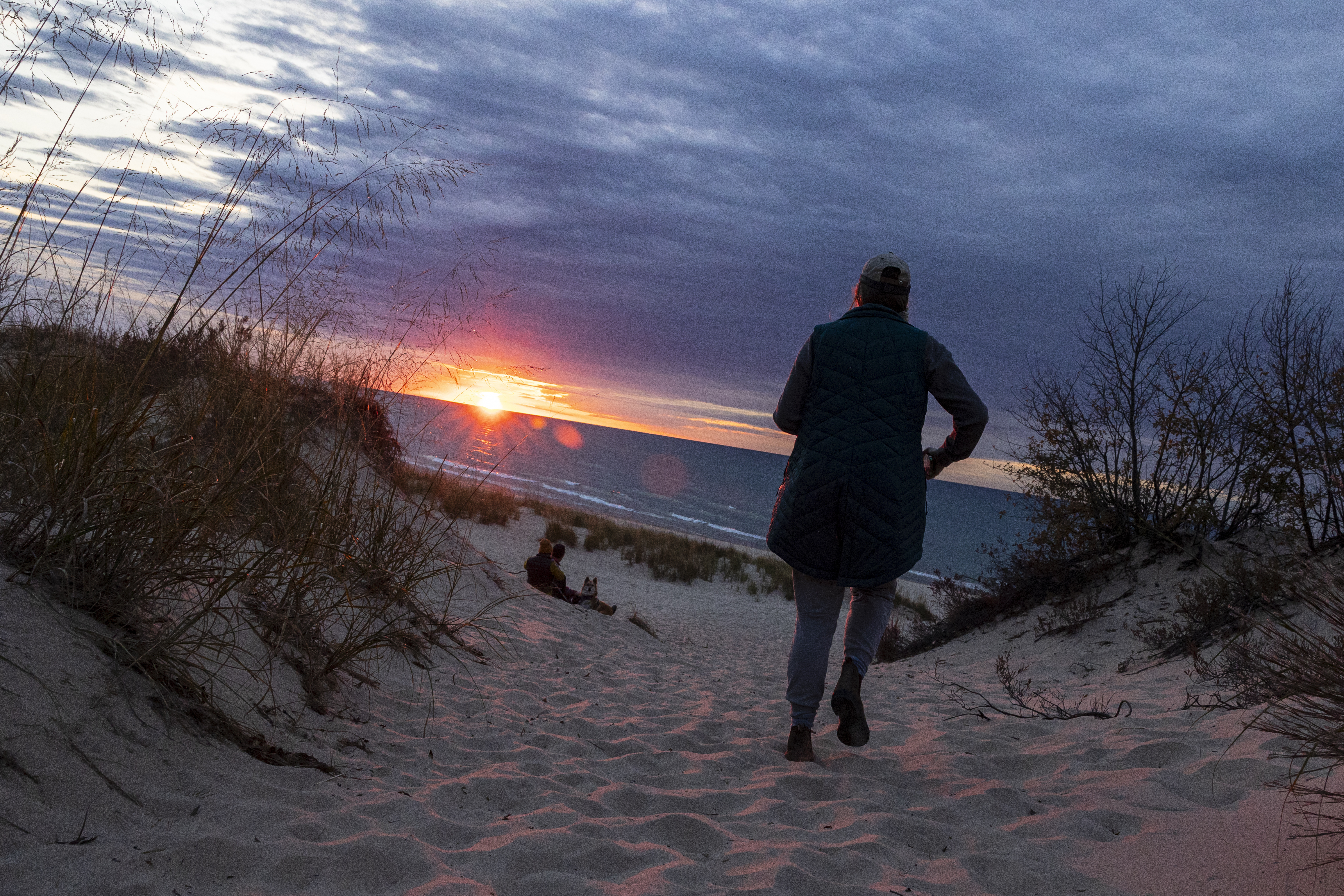 A person walks to the beach as the sun sets over Lake Michigan at Nordhouse Dunes Wilderness Area in Mason County, Mich. on Saturday, Oct. 12, 2024.  