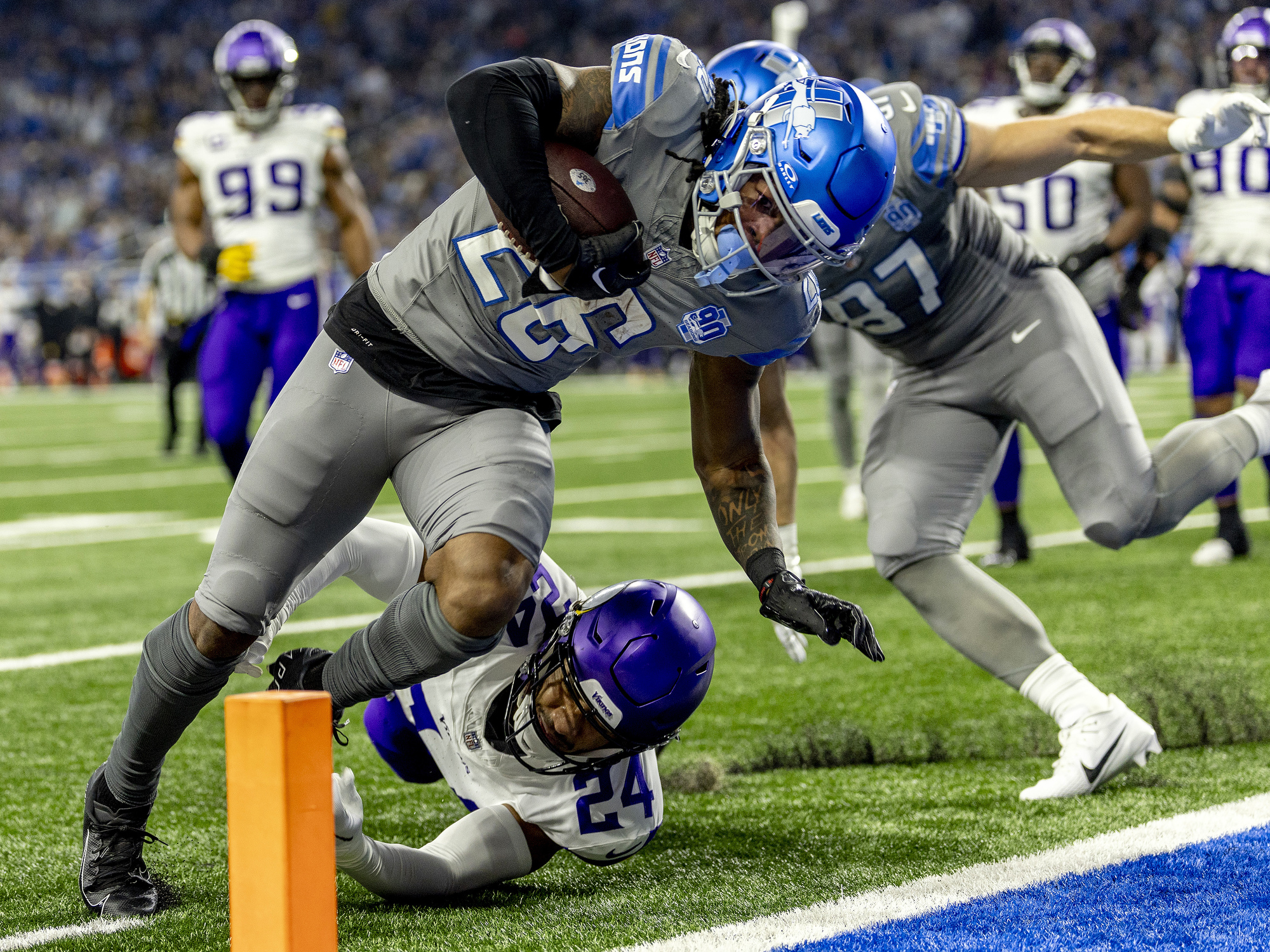 Detroit Lions running back Jahmyr Gibbs leaps over the hands of Minnesota Vikings safety Camryn Bynum to score a touchdown just past the pylon in the first half of the last regular season game against the Minnesota Vikings on Sunday, Jan. 7, 2024 at Ford Field in Detroit.