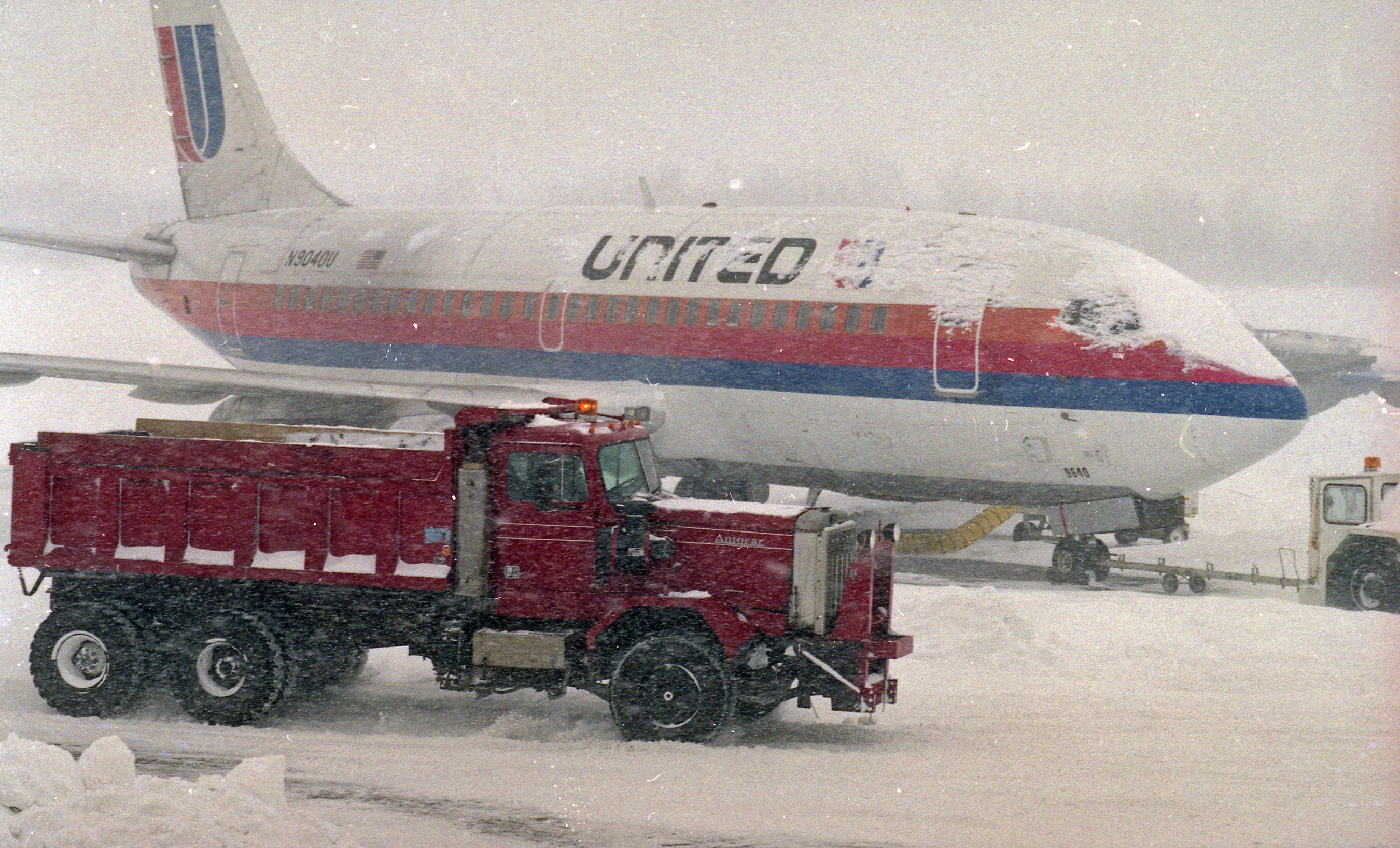 A truck loaded with snow passes a plane at Hancock Airport as crews try to remove snow from the Blizzard of 1993.