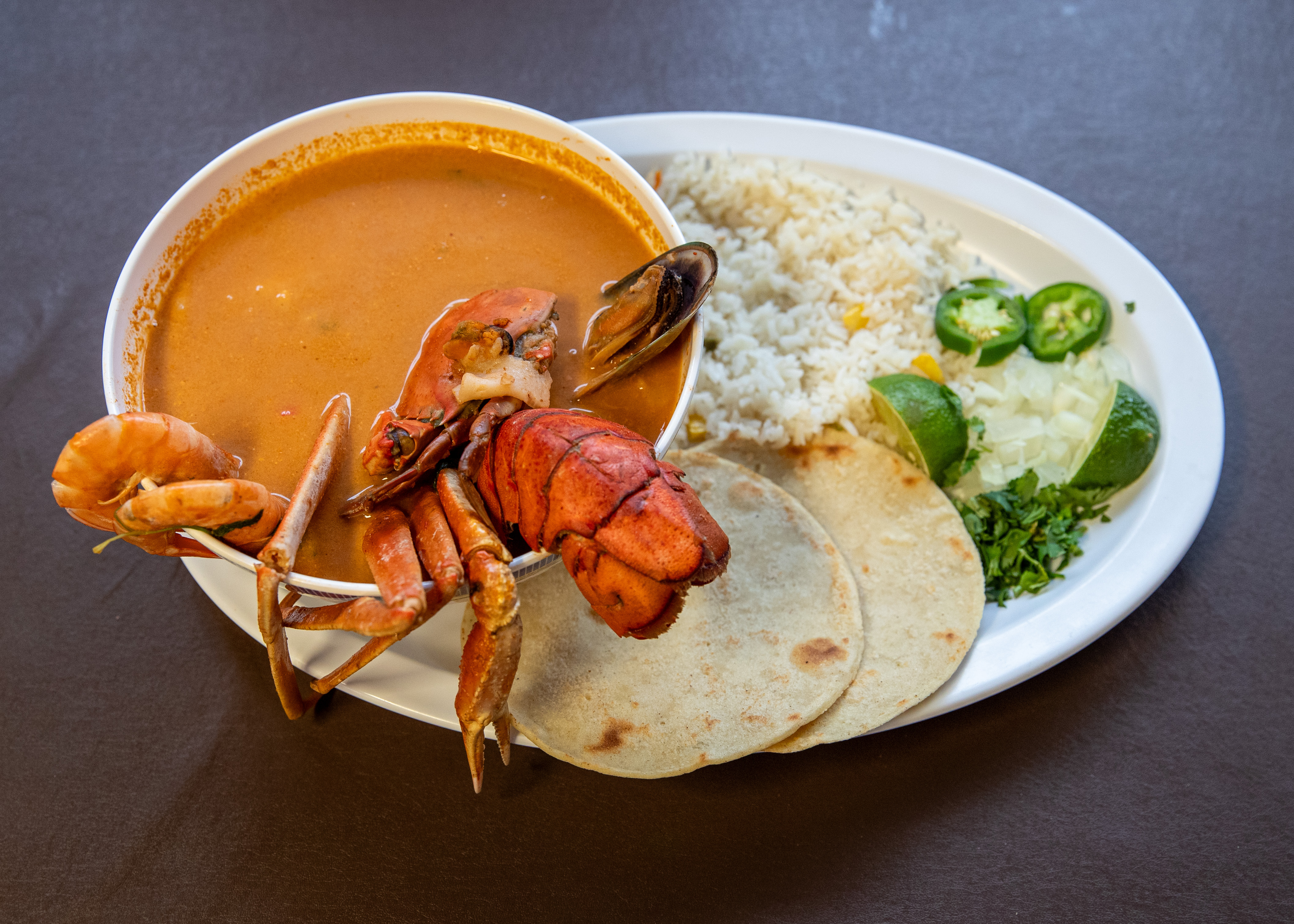 Mariscada Soup (seafood soup that includes lobster, fish, shrimp, mussels, and octopus) that comes with rice, two homemade tortillas, onion, lime, jalapeño for $26.98 at Pupuseria El Salvador in Wyoming on Thursday, Oct. 19, 2023. (Cory Morse | MLive.com)
