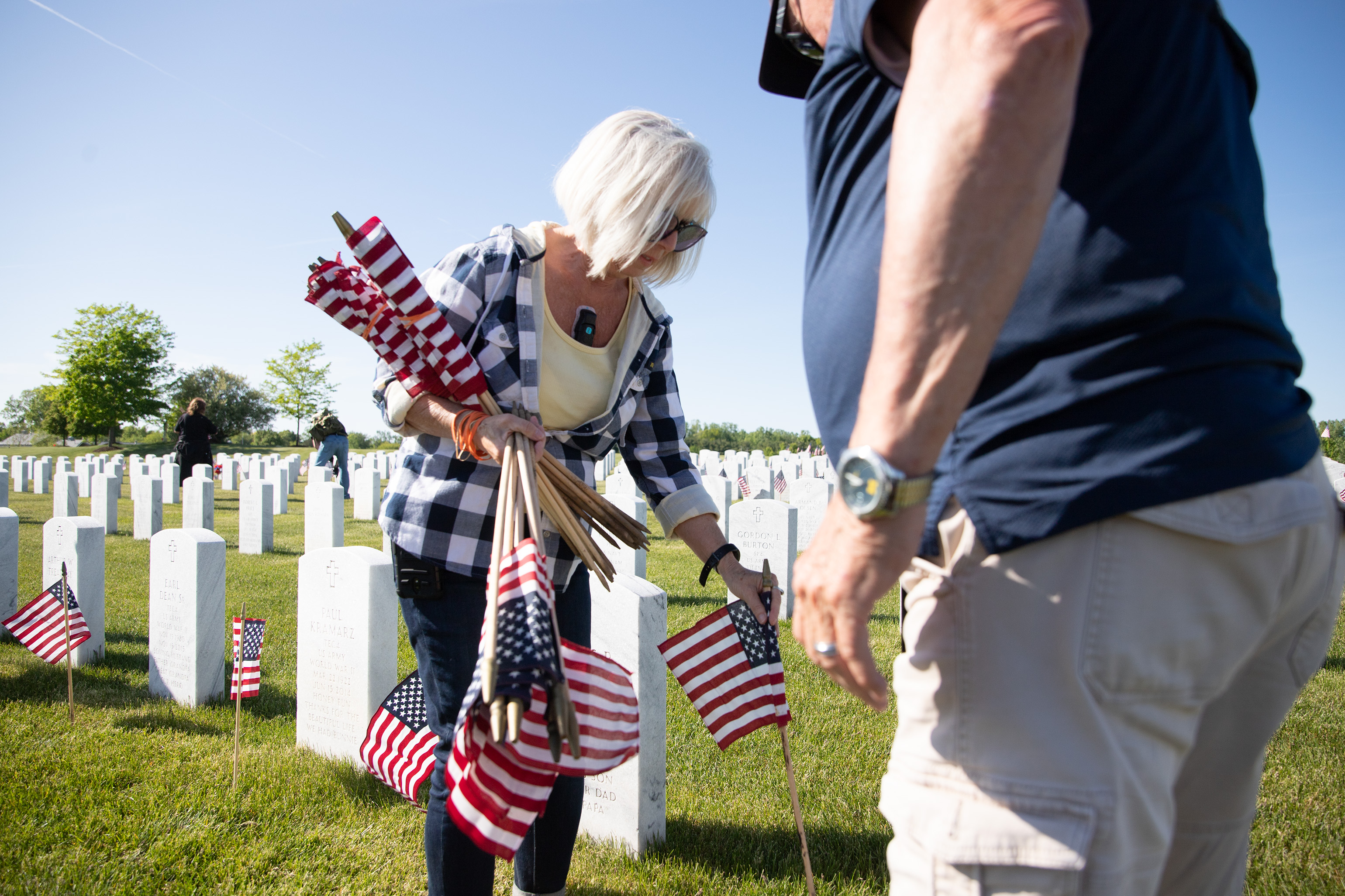 Volunteers place flags on graves ahead of memorial day at the Great