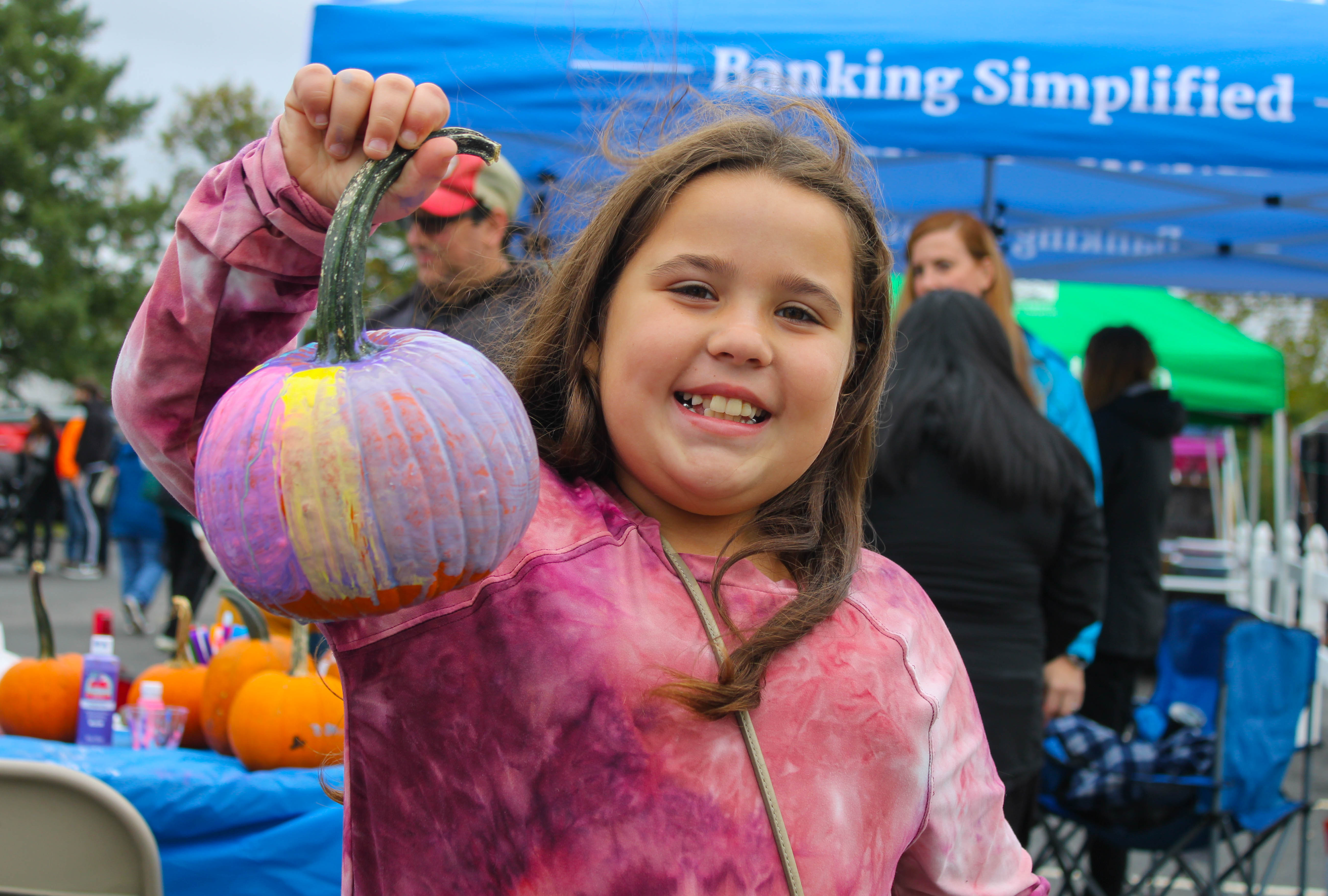 Marlie Hernandez, 8, present her freshly painted pumpkin at the Harvest Day Festival in Elmer, Saturday, Oct. 1, 2022.