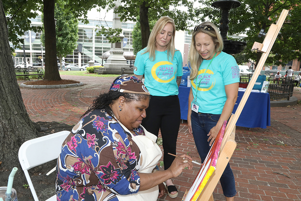 Rachael Casey from the CDC Foundation and Karen Finn from the Springfield Cultural Partnership watch artist Susan Duncan create a painting of Louis Armstrong at Chalk for Change 2022 taking place at Court Square in Springfield on July 16th. (Ed Cohen Photo)