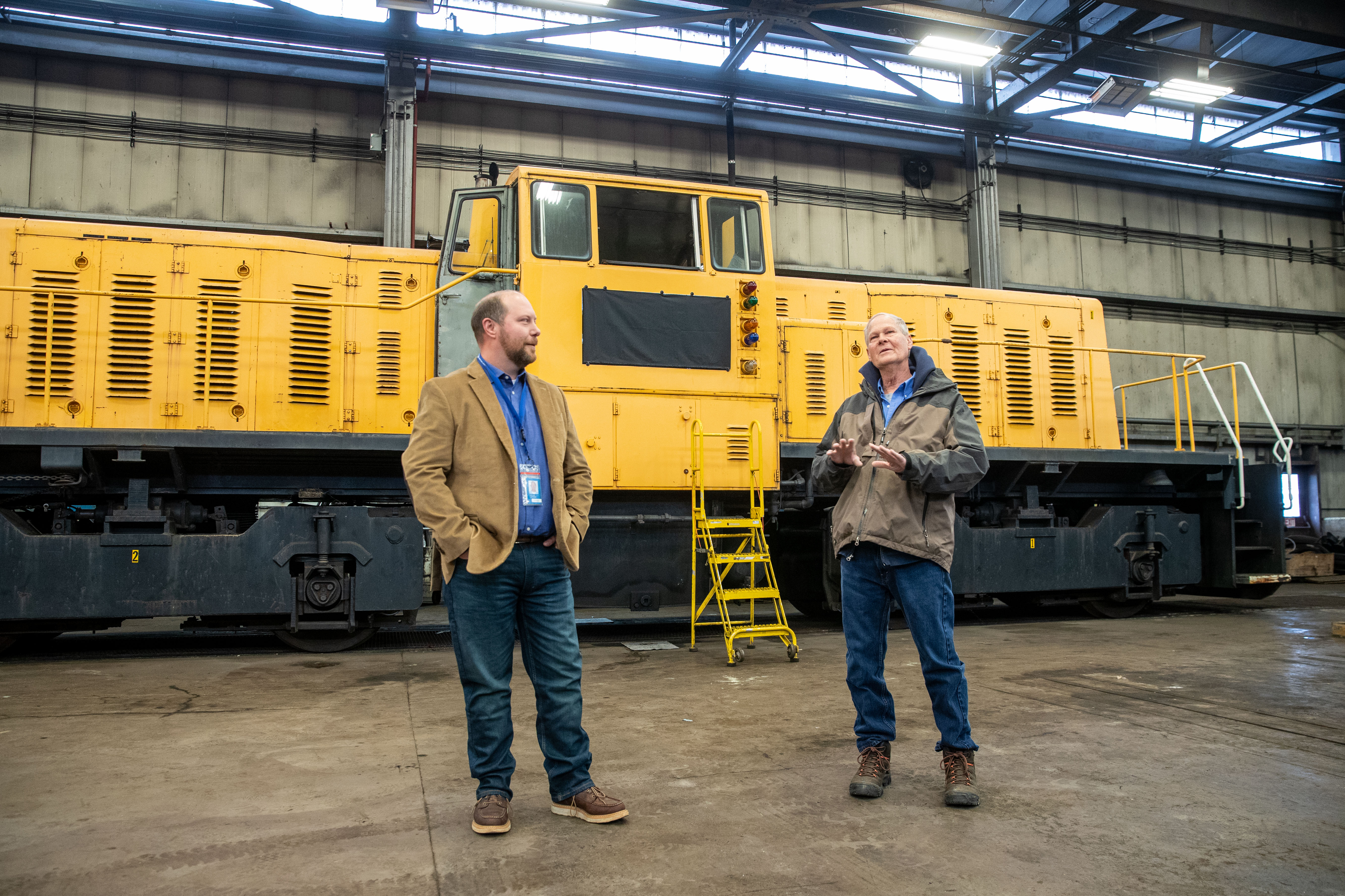 Nathan Hoffman, left, director of operations at the Consumers Energy J.H. Campbell plant, and Jeff DuPilka, president of Coopersville and Marne Railway, speak in front of a 1979 GE diesel train locomotive at the plant in Port Sheldon Township on Monday, Feb. 13, 2023. Consumers Energy is donating the locomotive to the Coopersville and Marne Railway. (Cory Morse | MLive.com)