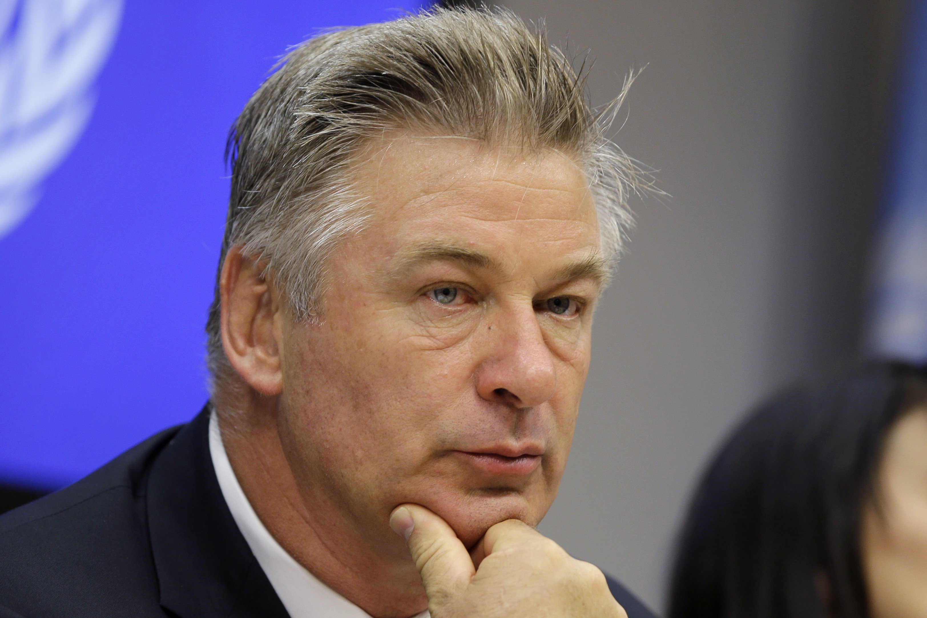 Alec Baldwin wearing a New York Jets jersey filming a football